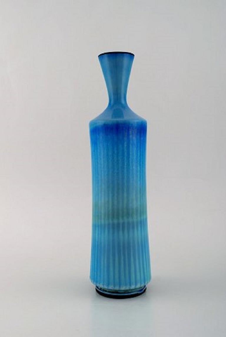 Berndt Friberg for Gustavsberg Studio hand. Large modernist vase in glazed ceramics. Beautiful glaze in light blue shades. Dated 1965.
Measures: 30 x 8.5 cm.
In very good condition.
Incised signature.
   