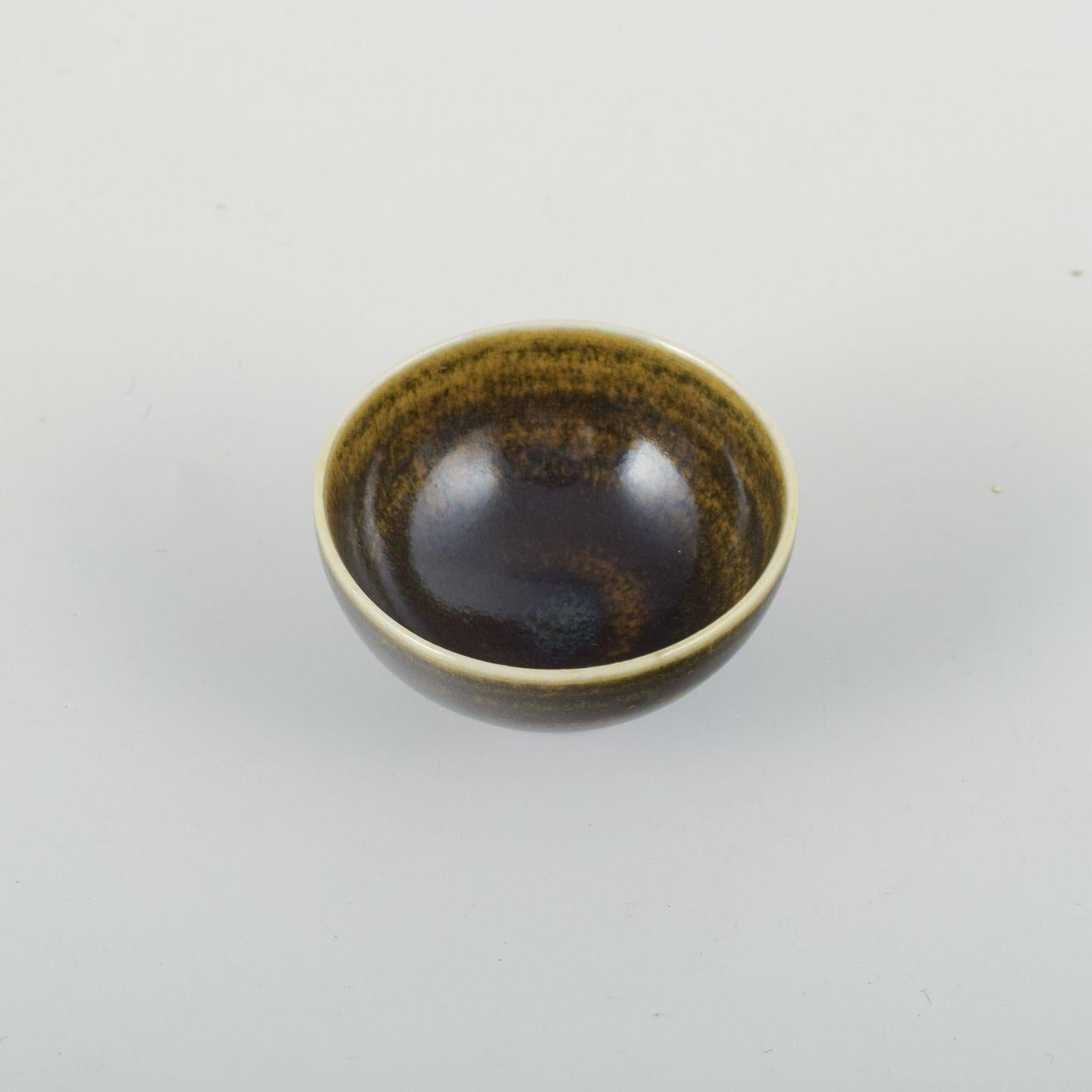 Berndt Friberg pour Gustavsberg Studio, Suède.
Petit bol élégant en grès. Magnifiquement émaillé dans des tons brun foncé avec des effets de surface dorés. 
La forme simple et équilibrée met en évidence le sens unique des proportions et du travail