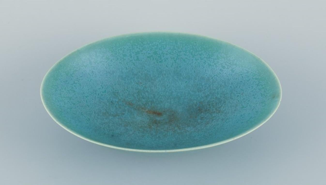Berndt Friberg (1899-1981) for Gustavsberg, Sweden.
Oval ceramic bowl in eggshell glaze with green-blue tones.
Approximately 1970.
Marked.
In good condition with a small chip on the edge - see photo.
Dimensions: Length 21.0 cm x Width 14.5 cm x