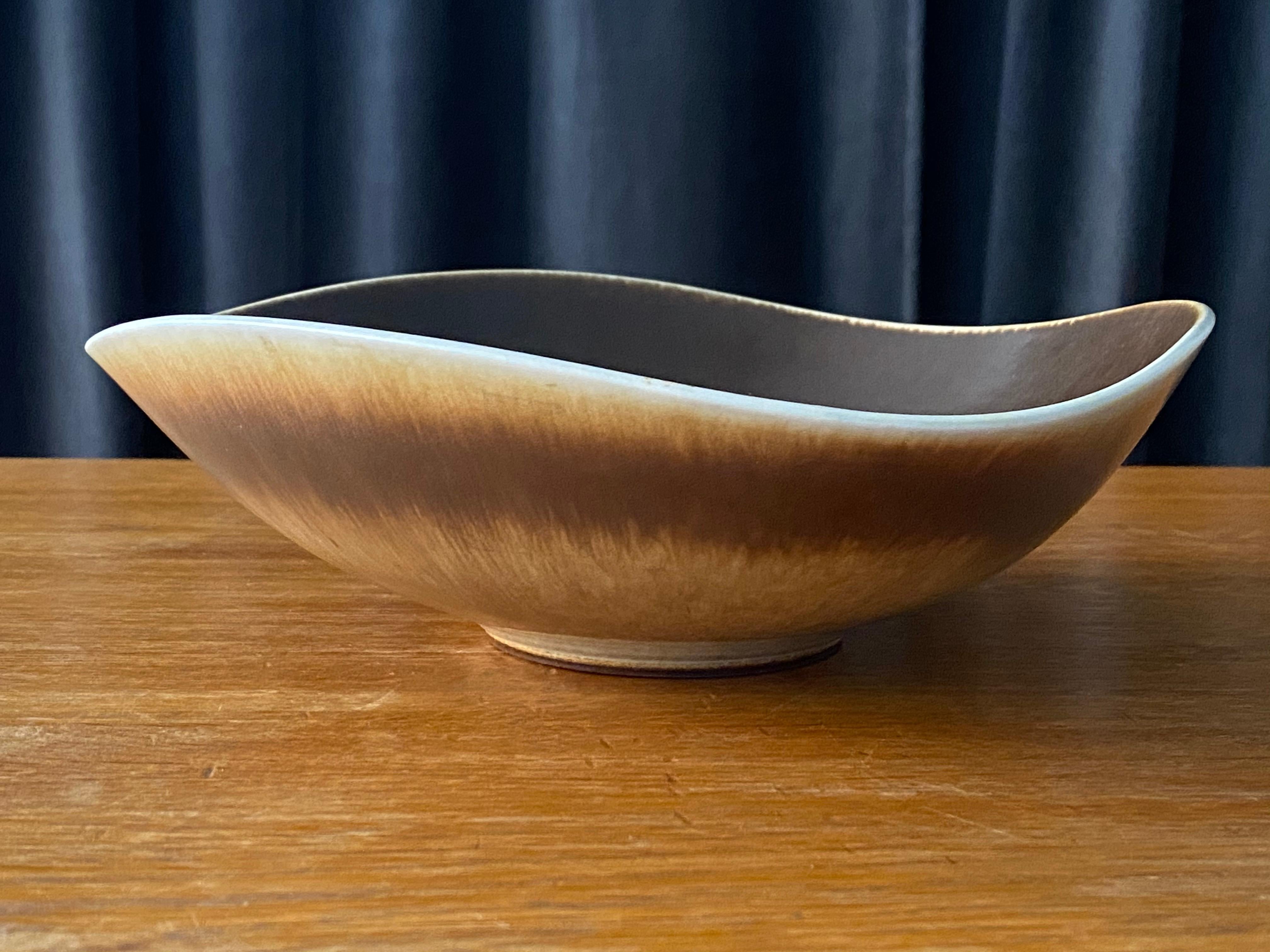 An organically shaped and sizable ceramic stoneware bowl / dish by Berndt Friberg for the iconic Swedish firm Gustavsberg. Signed. The highly artistic glaze contains brown / beige and white pigments.

Other ceramicists of the period include Berndt