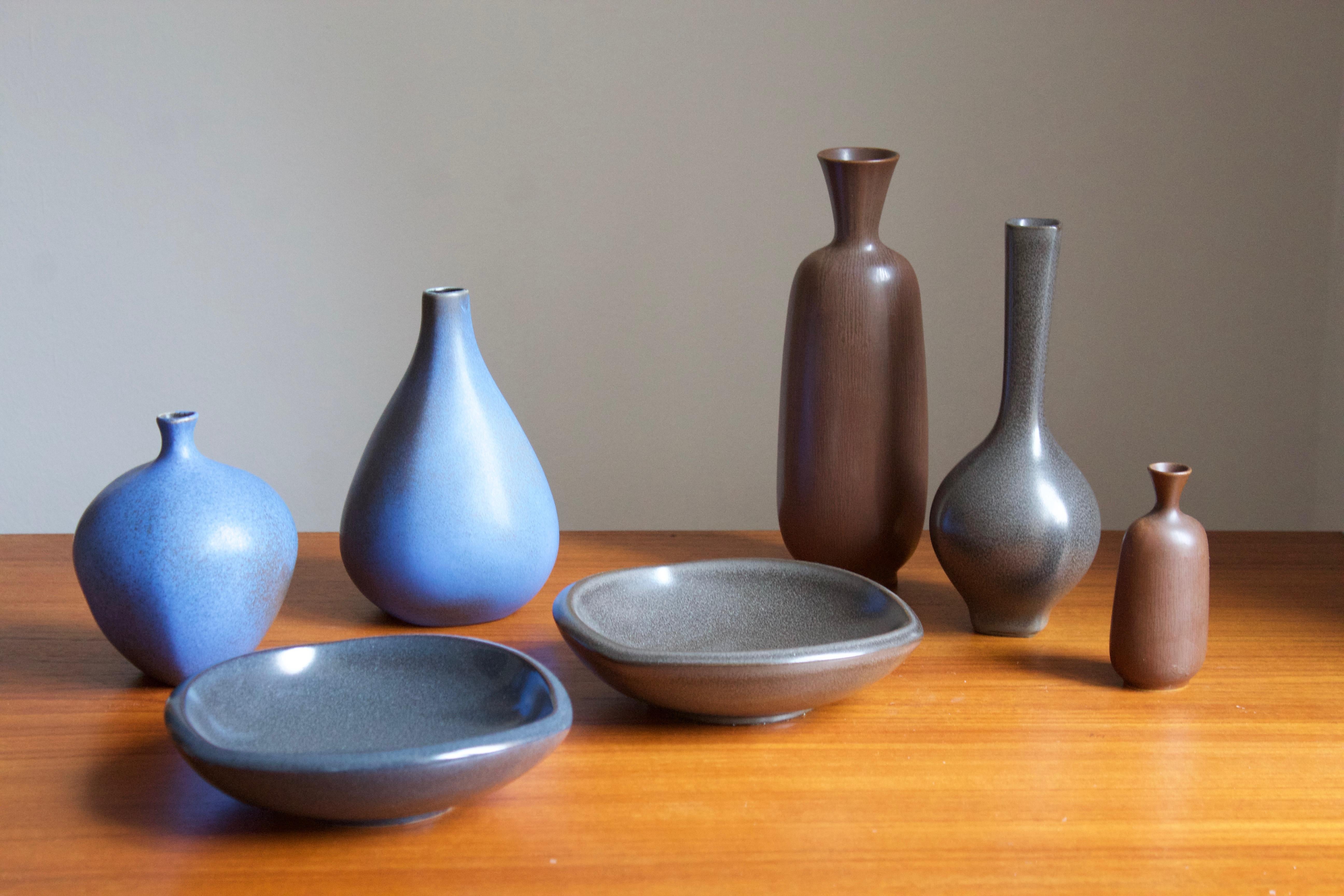 A group of 7 organically shaped vases and bowls / dishes all with simple monochrome glazing. Designed by Berndt Friberg for the Swedish firm Gustavsberg. Some with paper labels. 

Stated dimensions are off the tallest brown vase.

Other