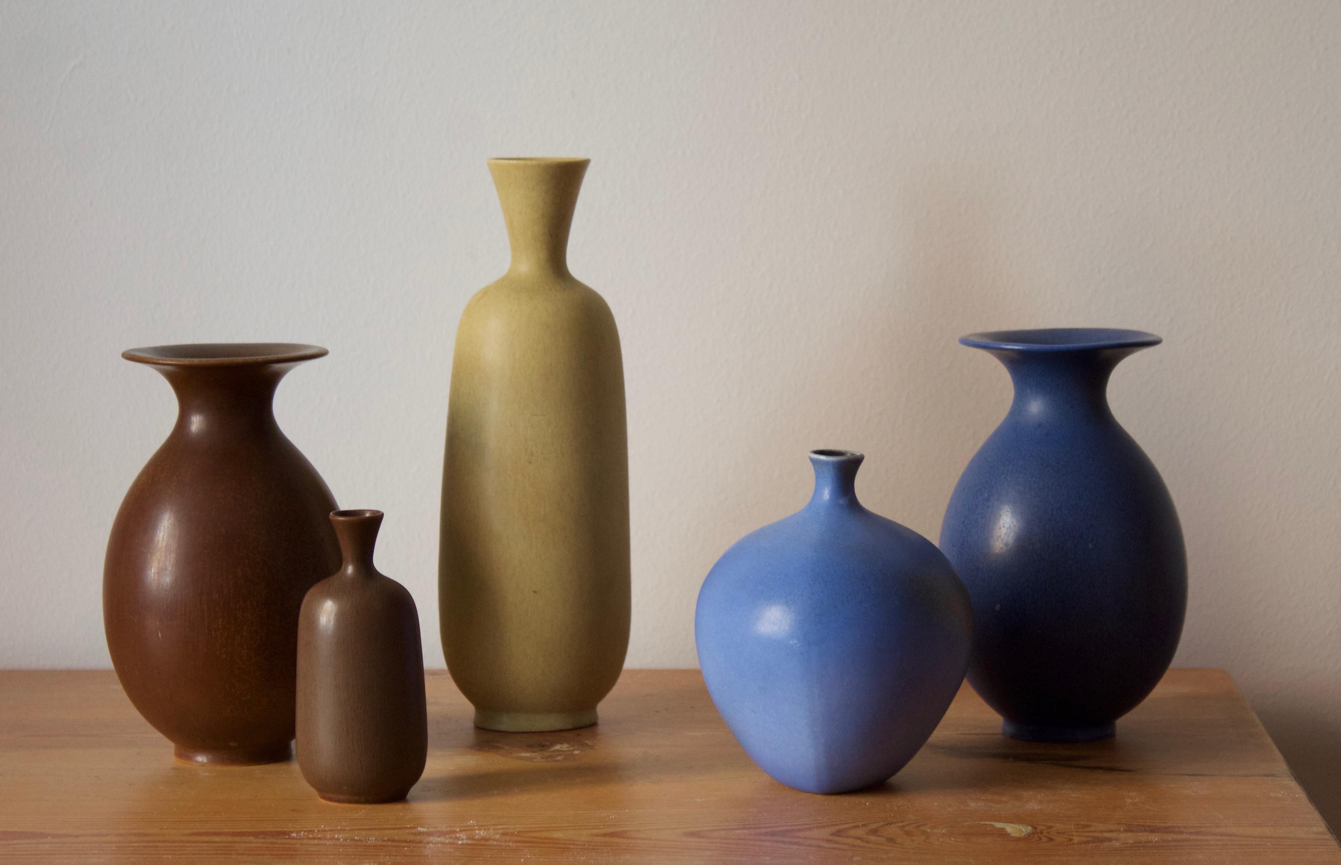 A group of 5 organically shaped vases, all with simple monochrome glazing. Designed by Berndt Friberg for the Swedish firm Gustavsberg. Some with paper labels and stickers to backside. 

Stated dimensions are off the tallest brown vase.

Other