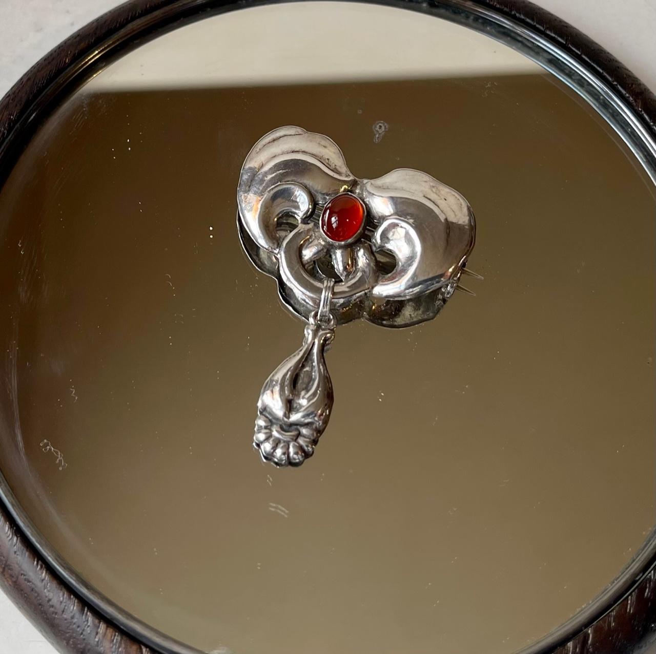 Period Jugend silver brooch set with a deep red garnet stone in cabochon. Large size with two sections attached with a hoop. Markings: 826, S, BH (Bernhard Hertz). Measurements: H: 50 mm, W: 40 mm.

The Hertz workshop in Copenhagen were closely