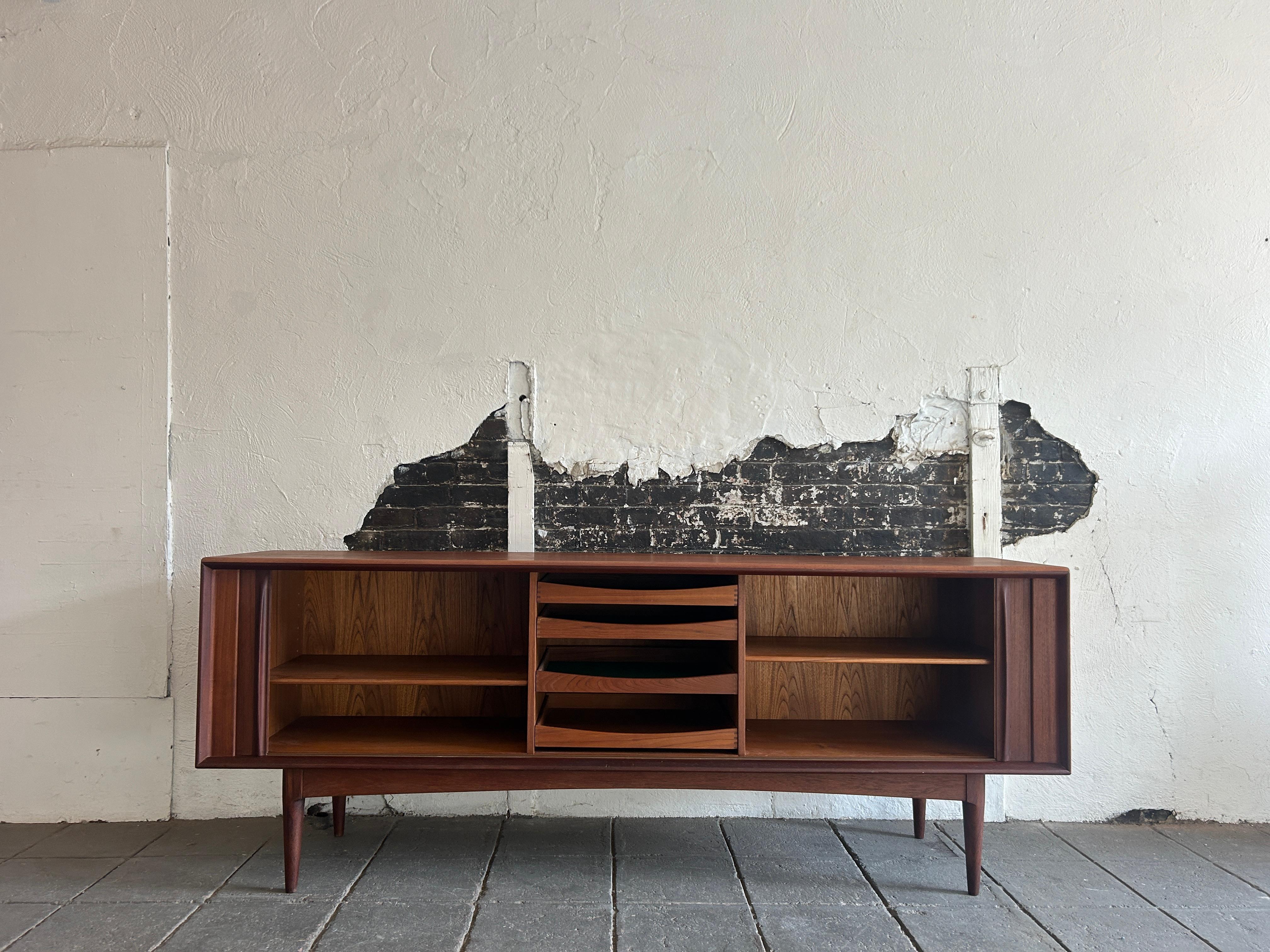 Stunning Bernhard Pedersen & Son mid century long low Danish teak credenza sideboard with 2 tambour sliding doors and 4 center drawers also has 3 adjustable shelves. High quality teak wood credenza with sculpted teak handles. Very clean Danish