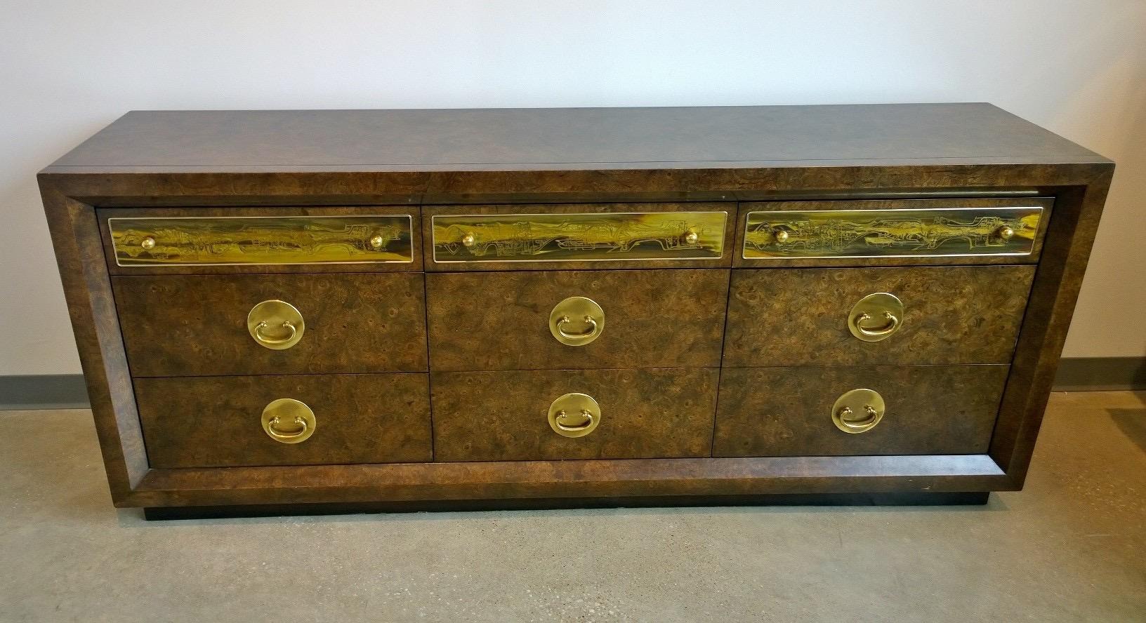 The offered piece is a signed Mid-Century Modern Bernhard Rohne for Mastercraft dresser or sideboard in burl wood and etched brass accents and brass hardware. The sideboard or dresser is an outstanding example of the partnership between the