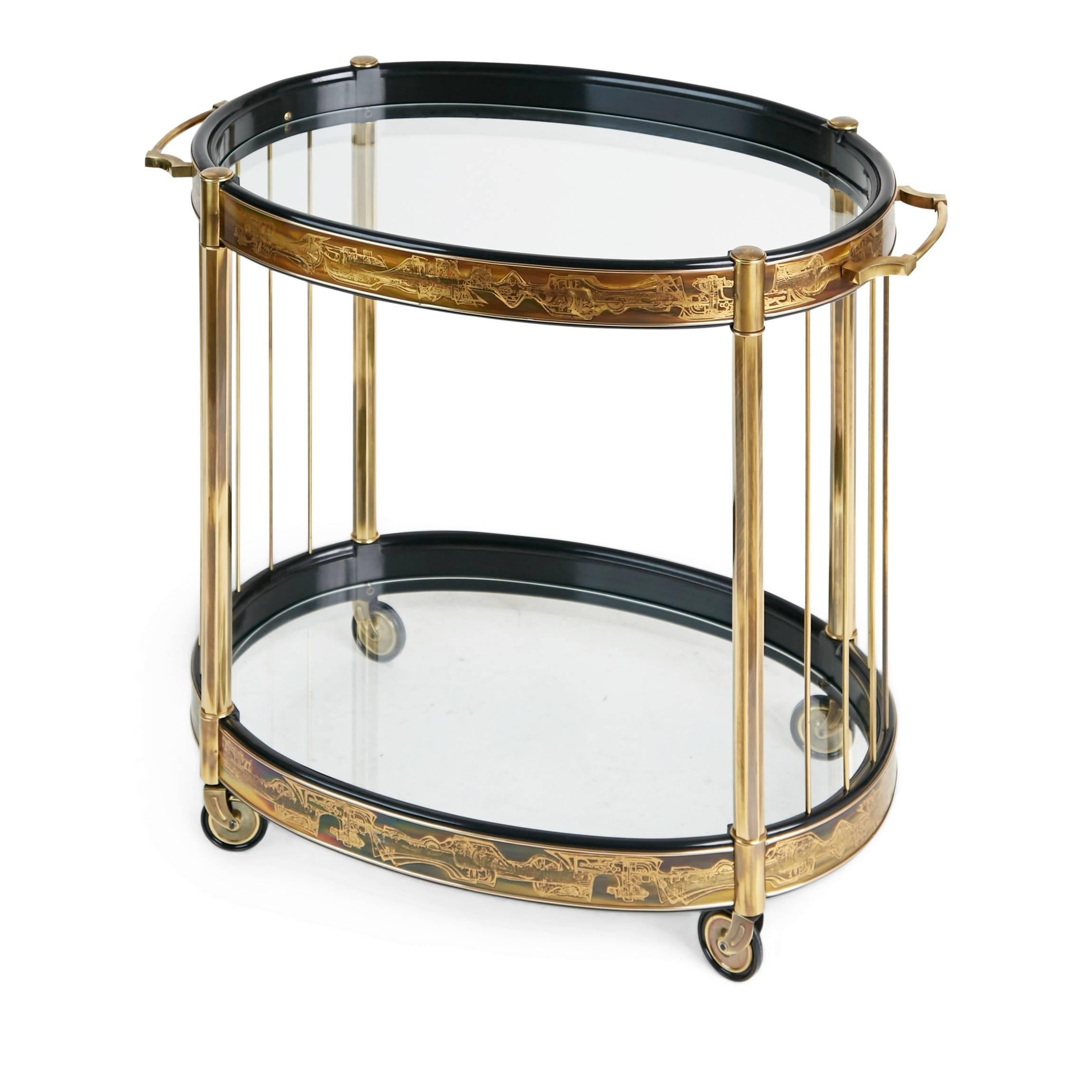 Exquisitely executed oval bar cart by Bernhard Rohne for Mastercraft. Featuring black lacquered and acid etched wrapped brass panels displaying an abstract freeform design. The cart has gleaming brass legs and polished brass rods that support the