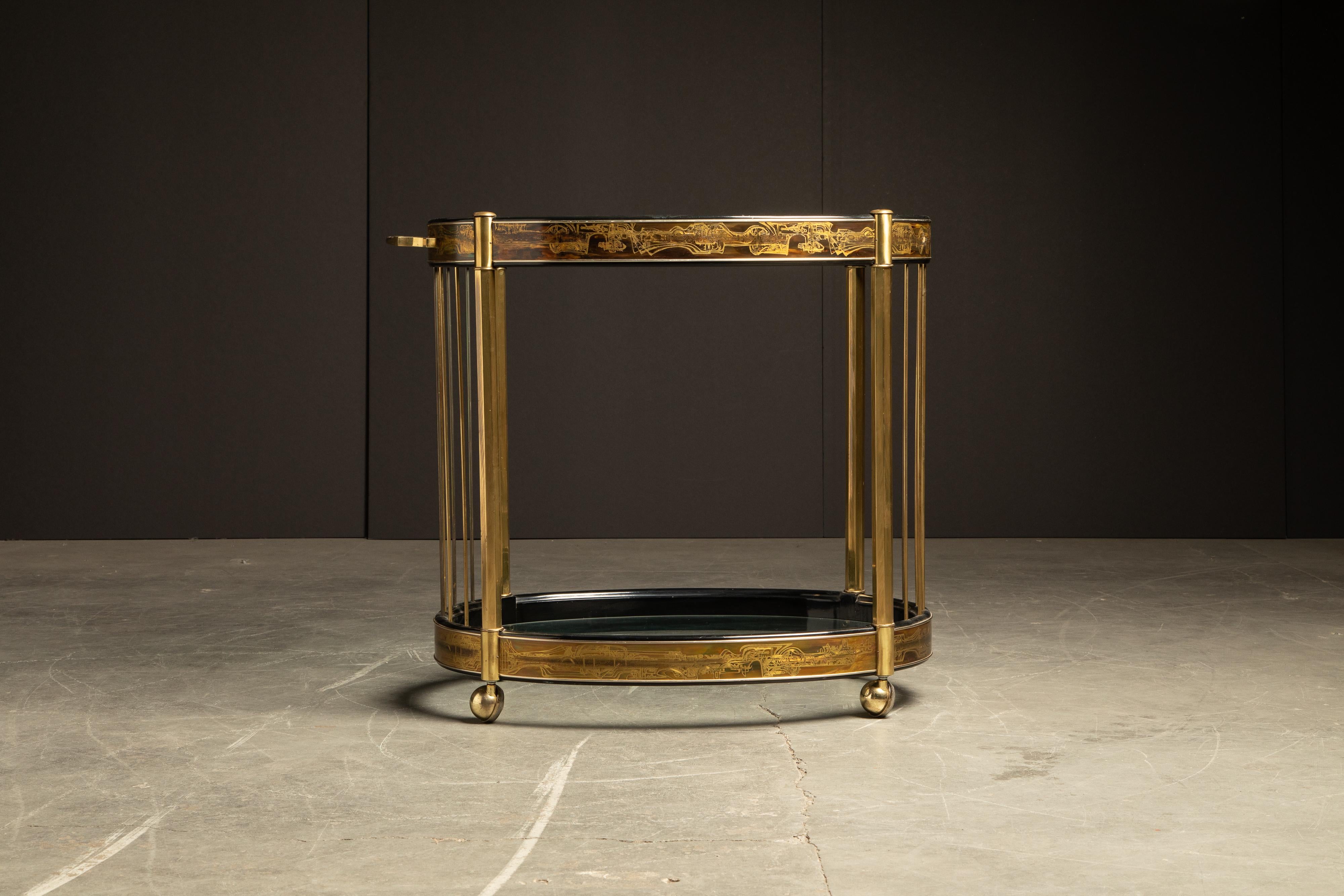 Exquisitely executed oval bar cart by Bernhard Rohne for Mastercraft. Featuring black lacquered and acid etched wrapped brass panels displaying an abstract freeform design. The cart has gleaming brass legs and brass rods that support the two glass