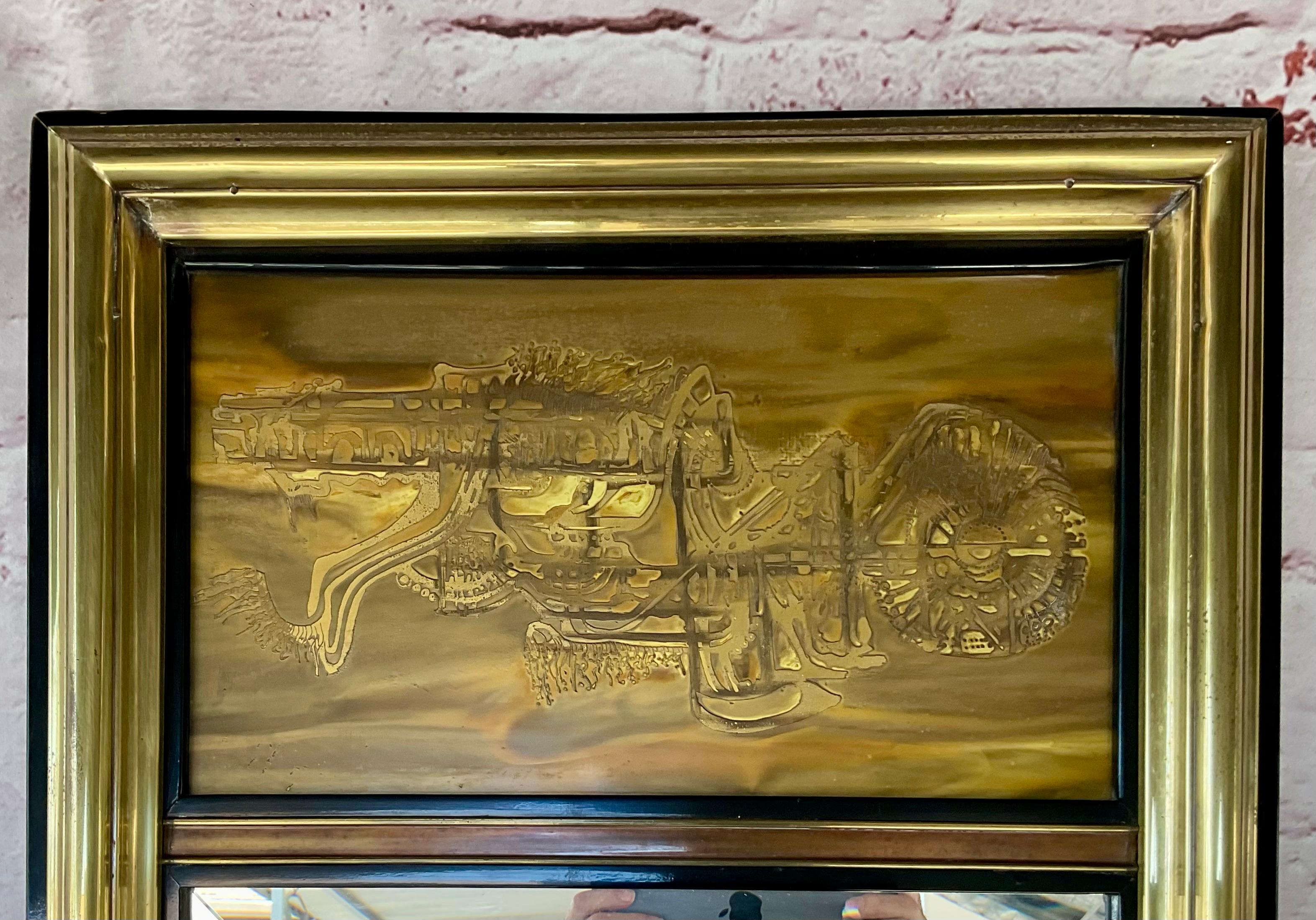Miroir mural en laiton gravé à l'acide Bernard Rohne pour Mastercraft. Le miroir est un objet haut et rectangulaire à la silhouette épurée et minimaliste, encadré d'or et de noir. Le panneau supérieur présente la technique complexe de gravure à
