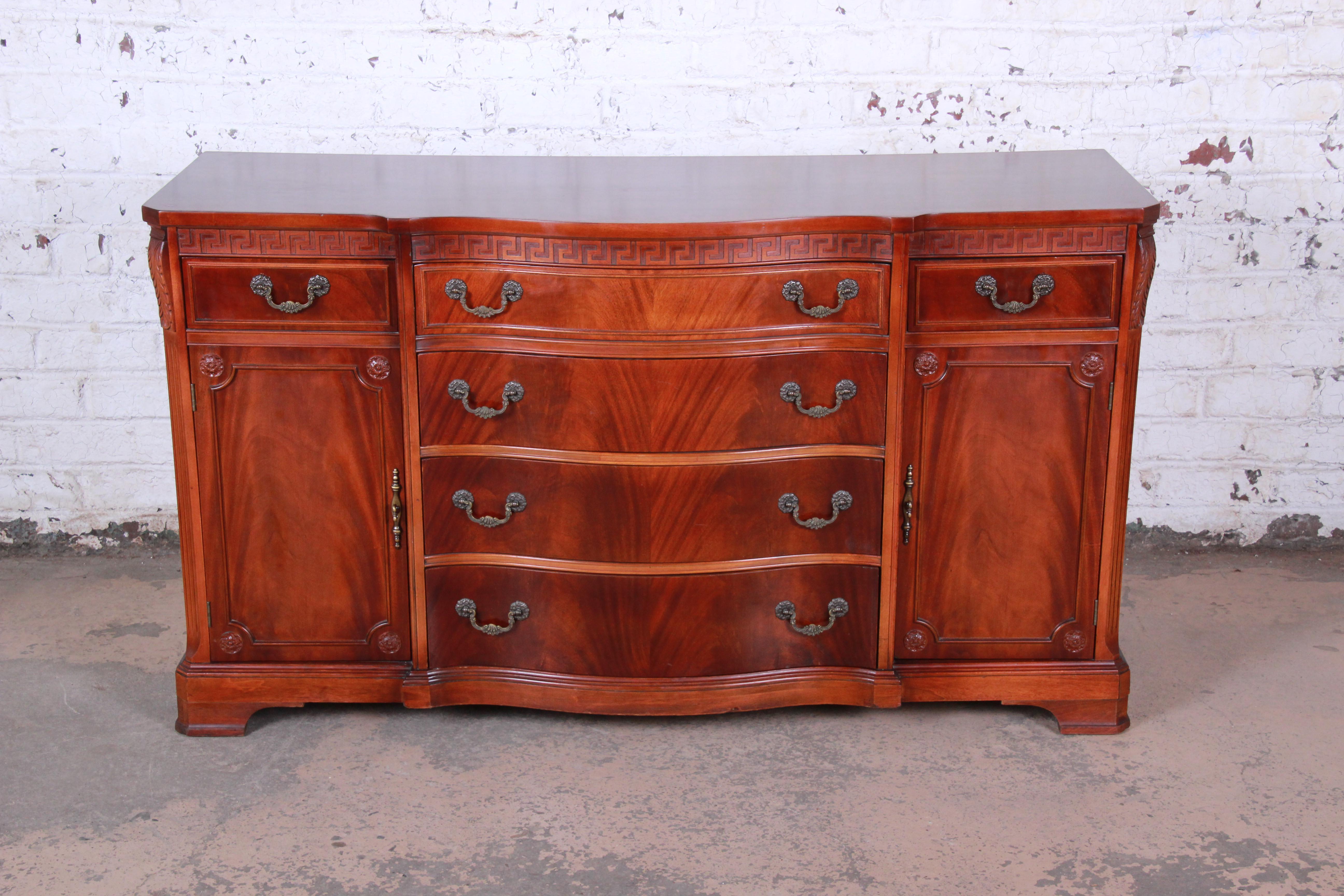 A stunning flame mahogany sideboard buffet by Bernhardt. The sideboard features gorgeous flame mahogany wood grain and nice carved details. It offer ample storage, with six dovetailed drawers and two storage cabinets with an adjustable shelf in