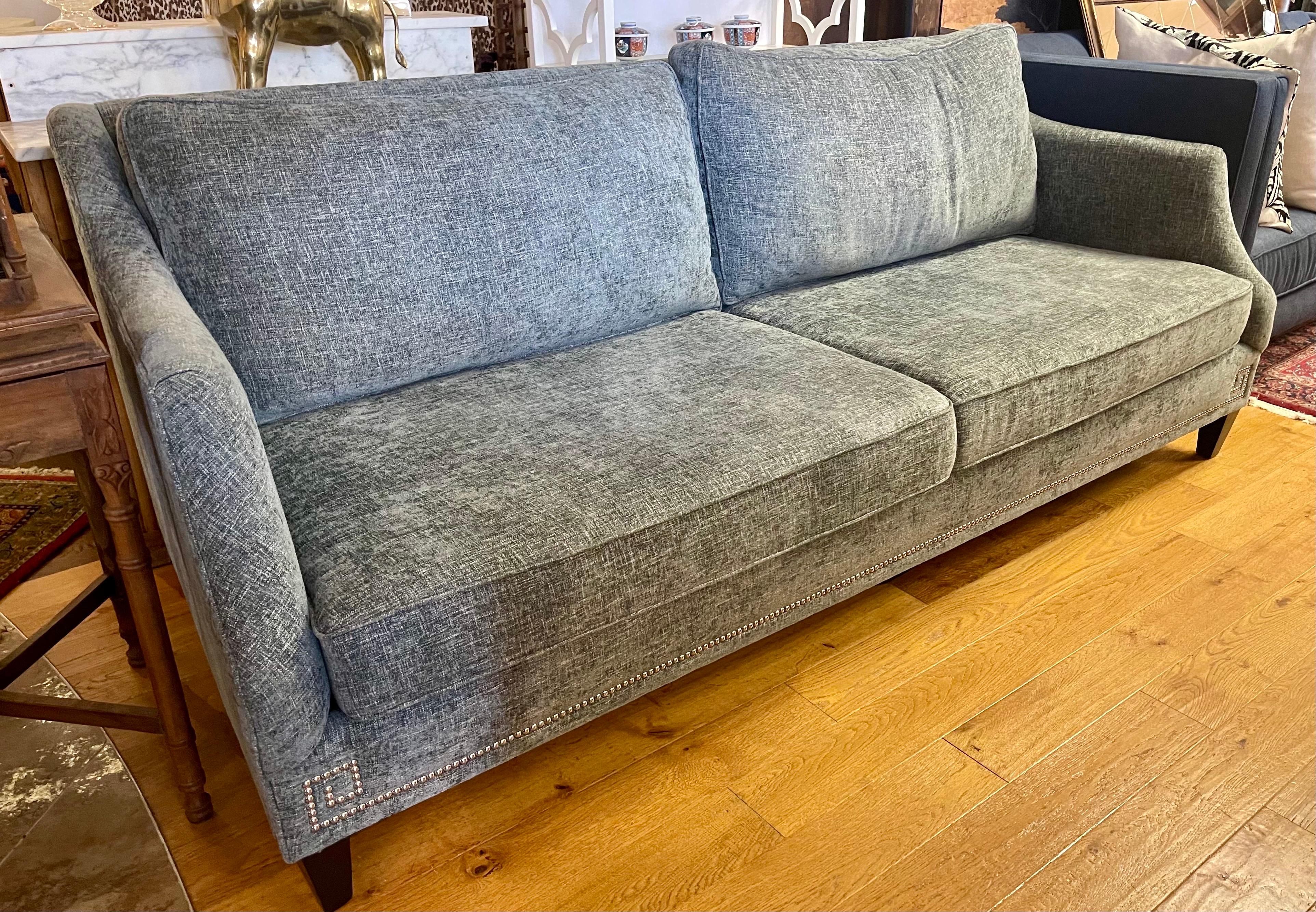 Solid gray chenille upholstered fabric gives this transitional nailhead sofa with a mid century flair a great presence.  Very elegant indeed.  We are based on the east coat in CT.  If your delivery address is east of Chicago we can probably do