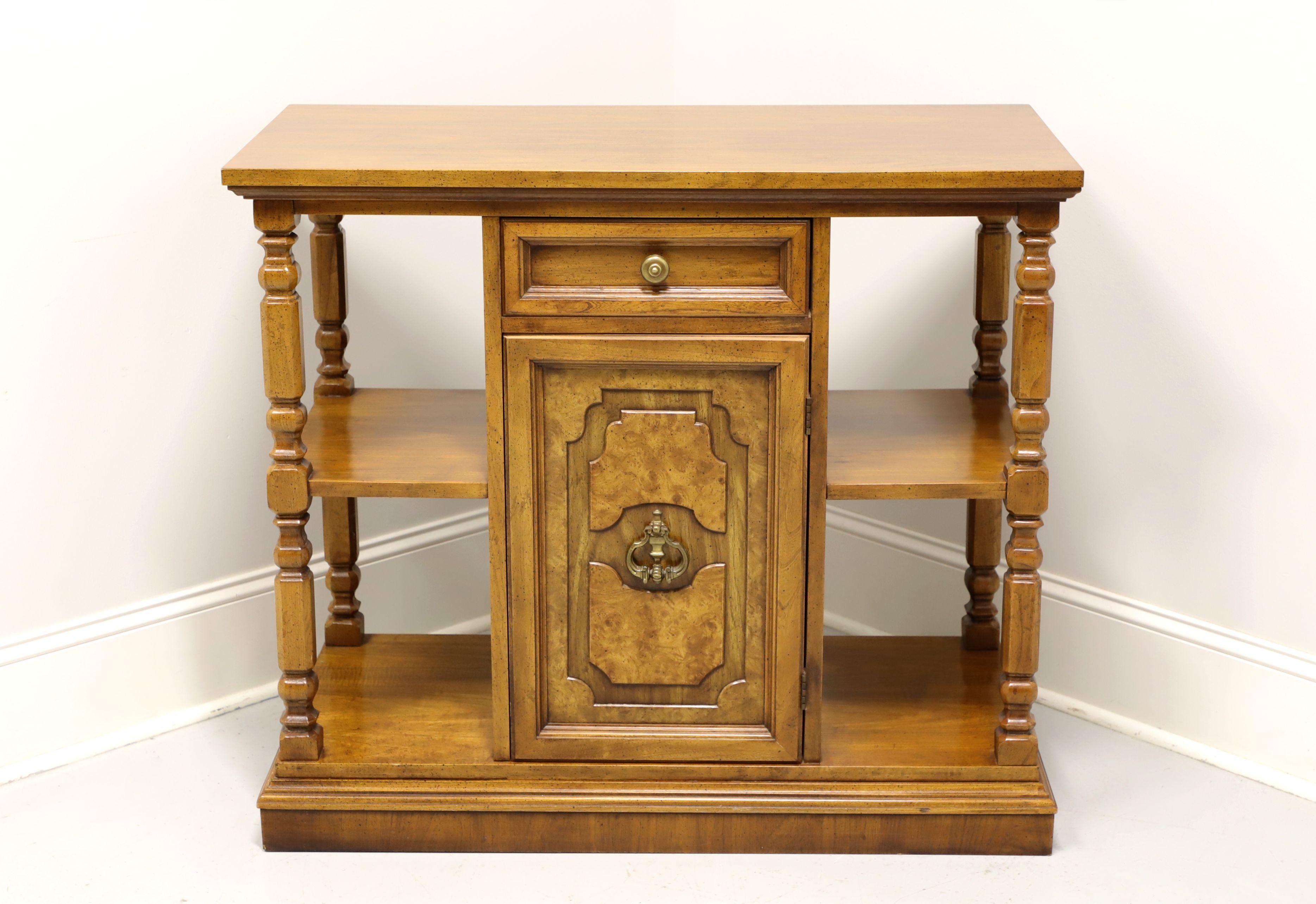 A Mediterranean style console cabinet with open shelves by Bernhardt. Walnut with a distressed finish, burl to door front, turned side posts and brass hardware. Features one dovetail drawer over a one door cabinet revealing a storage area with one