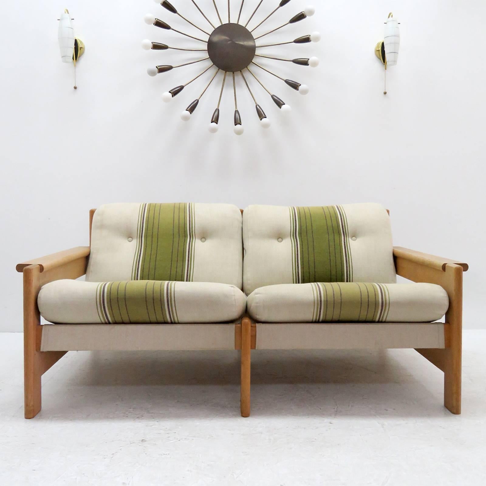 Bold and comfortable Danish modern two-seat sofa by Bernt Petersen, Denmark, 1970, oversized oak frame with dual colored cushions on canvas with leather straps.