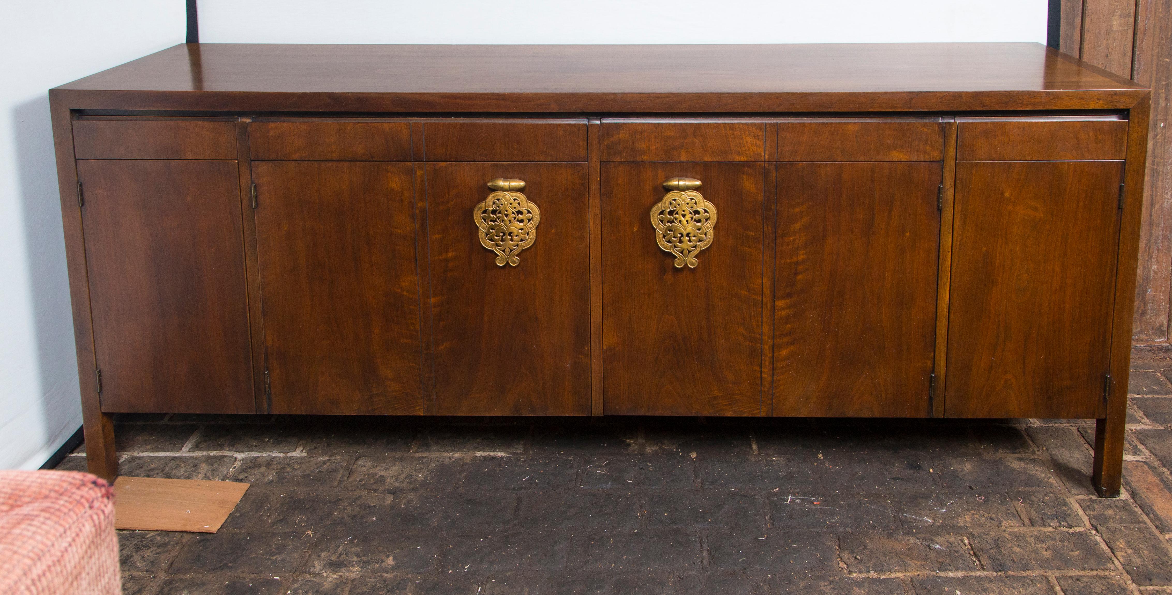 Bert England Asian Style Mid-Century Modern walnut sideboard or credenza. Manufactured by Johnson Furniture Co. Four flush drawers above the doors. A pair of large filigree Asian pulls on center doors.