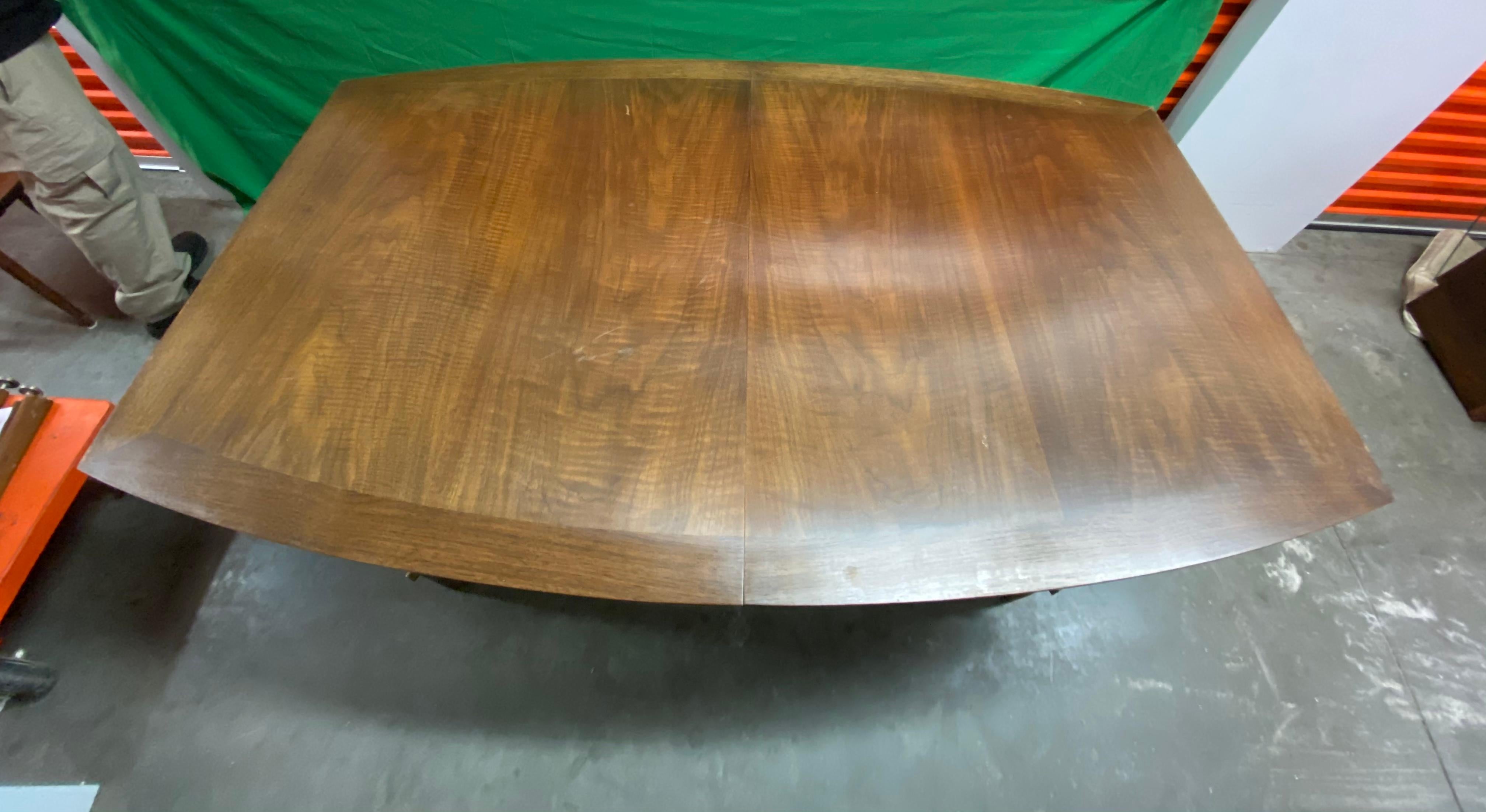 Bert England Mid-Century Modern walnut and brass dining table with curved shape. Designed by Bert England for Johnson Furniture. The table top is made of walnut with a flush walnut border and has a curved boat shape. The table top is supported by