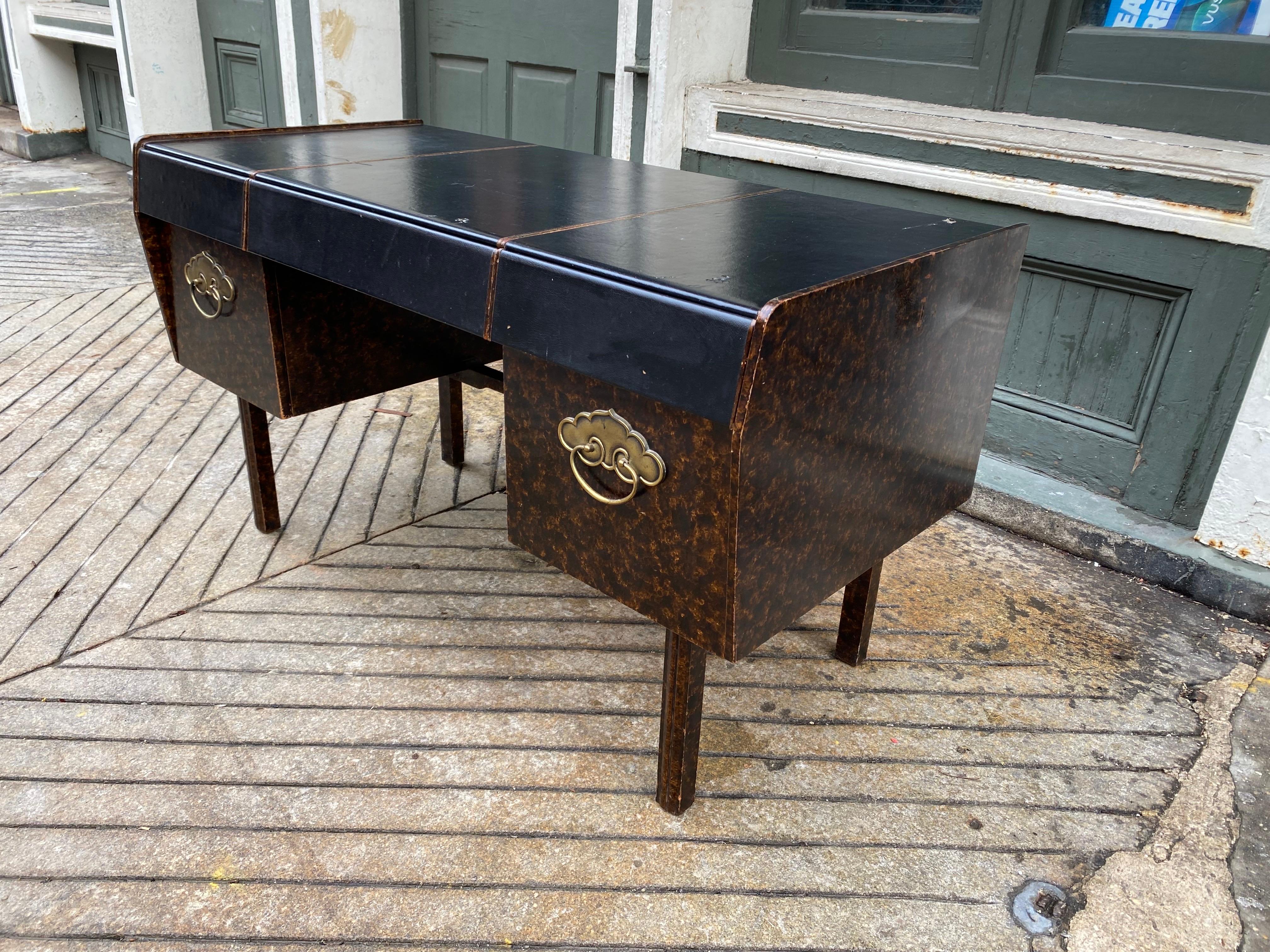 Bert England for John Widdicomb faux-Tourtise shell finish body with a black vinyl work surface and drawer fronts.  Asian inspired brass handles.  Desk is finished on all sides!  Finish shows some light wear and vinyl top shows some damage as seen