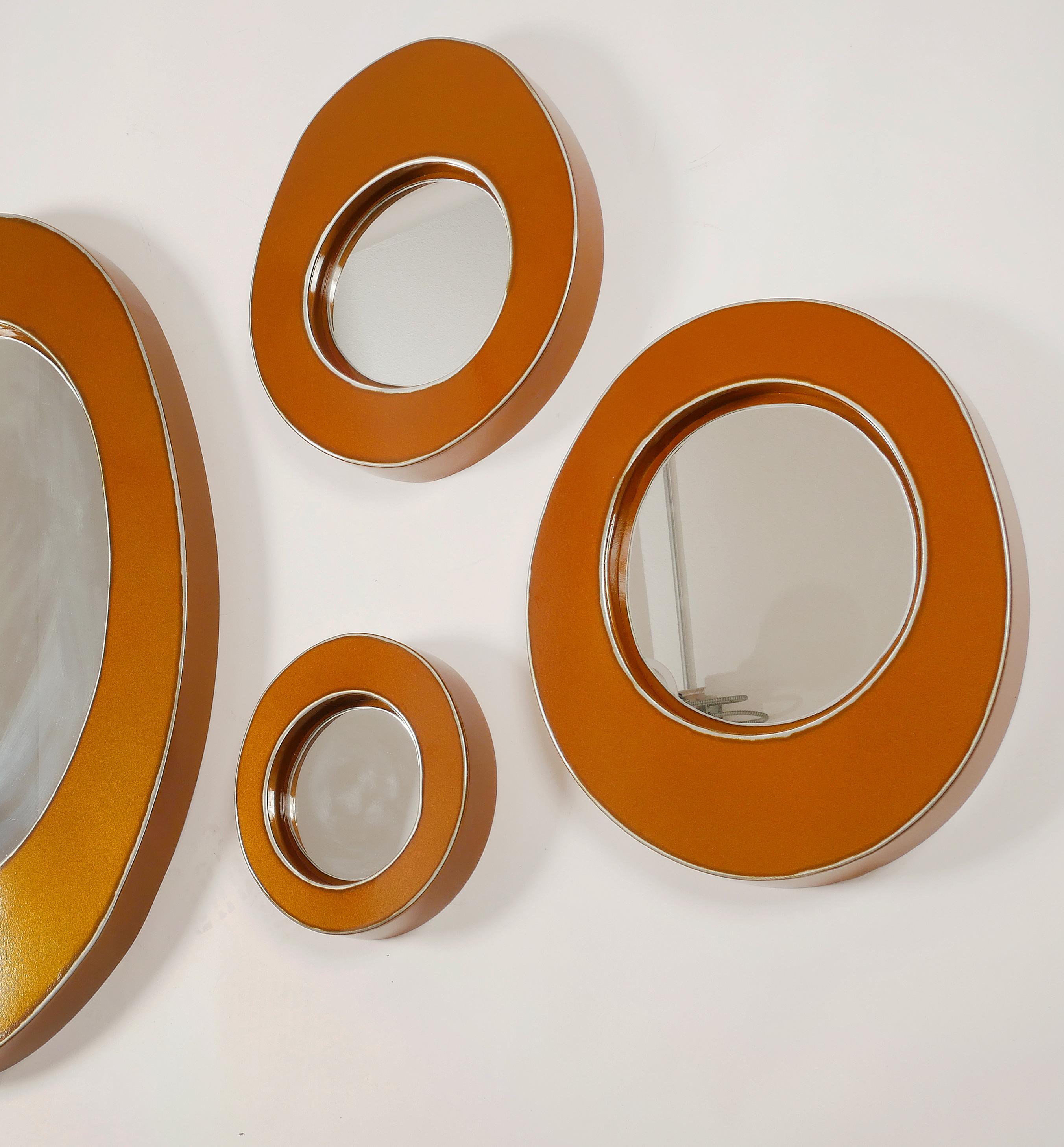 Bert Furnari Studio free-form abstract mirror group of 7

Offered for sale is a group of seven oval and round sculpted aluminum mirrors with a powder-coated orange/copper finish. The grouping can be arranged as desired for your setting. 
Bert