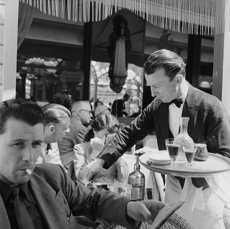 "Cafe Culture" by Bert Hardy

A waiter serving clients on the terrace of a cafe on the Champs-Elysees, Paris, June 1951. 
Original publication: Picture Post - 5343 - Sunday Morning In The Champs-Elysees - pub. 23rd June 1951

Unframed
Paper Size: