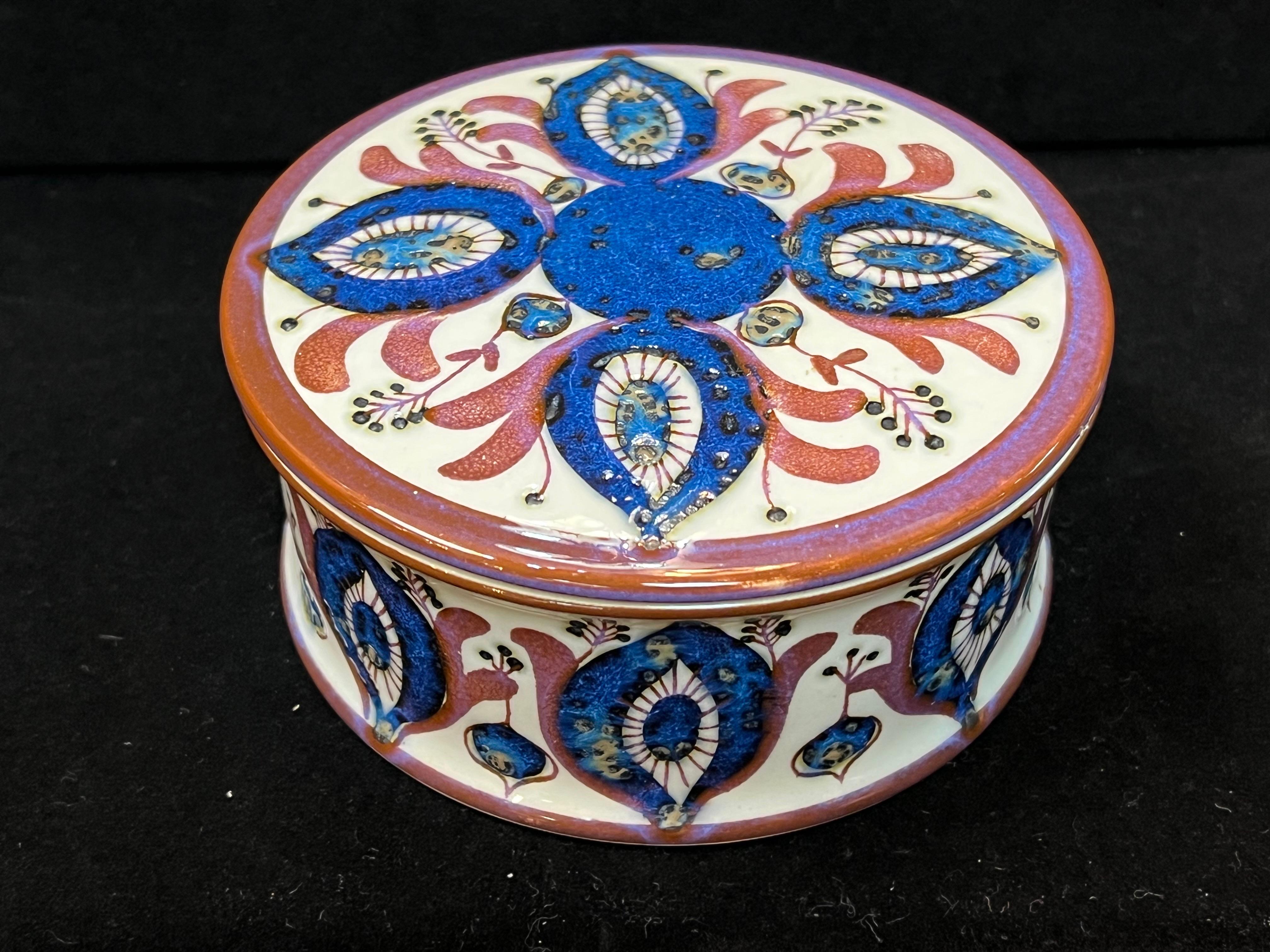 A vintage circa 1970s midcentury Danish modern faience ceramic box by Berte Jessen for Royal Copenhagen. This lidded circular box is fully marked and has a beautiful and colorful design. The lidded pot is decorated with stylized seed pod designs.