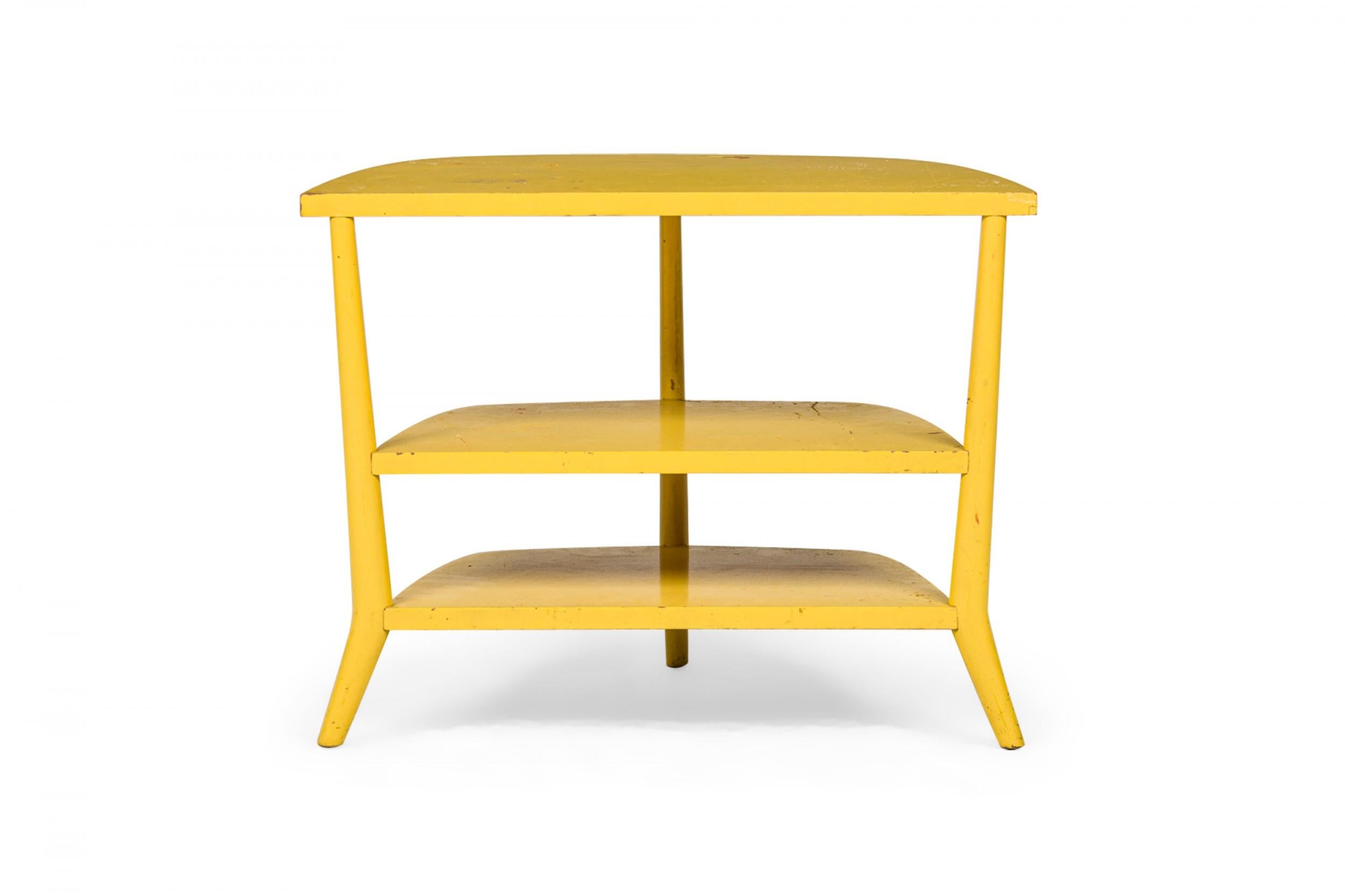 American Mid-Century three-tier end / side table with a demilune profile and three curved and tapered legs, with a yellow painted finish. (BERTHA SCHAEFER FOR SINGER & SONS).
 