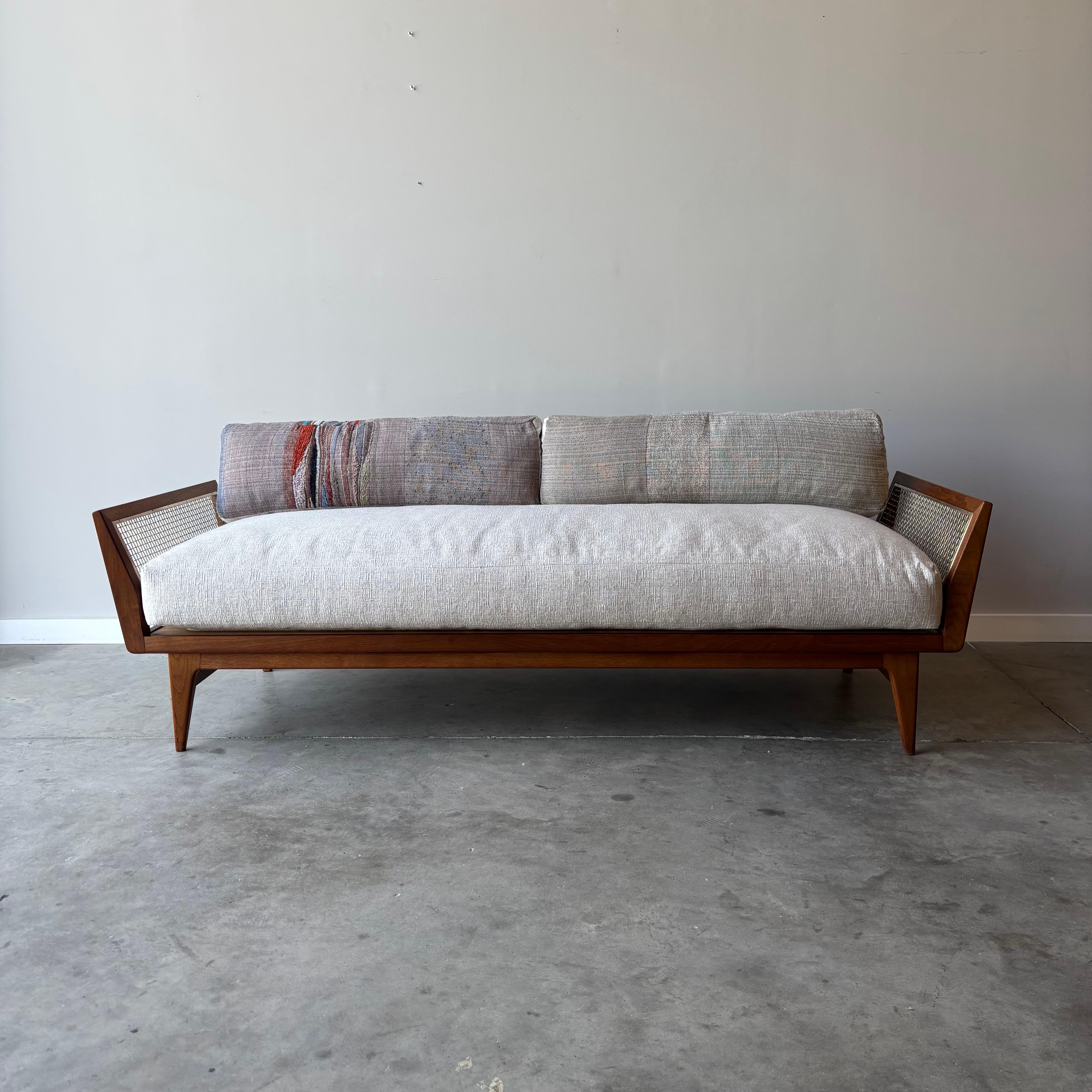 
Este elegante sofá presenta un característico armazón de nogal macizo con paneles decorativos de alambre de latón en los reposabrazos, creado por la diseñadora Bertha Schaefer para Singer & Sons hacia 1954. La pieza formaba parte de la apreciada