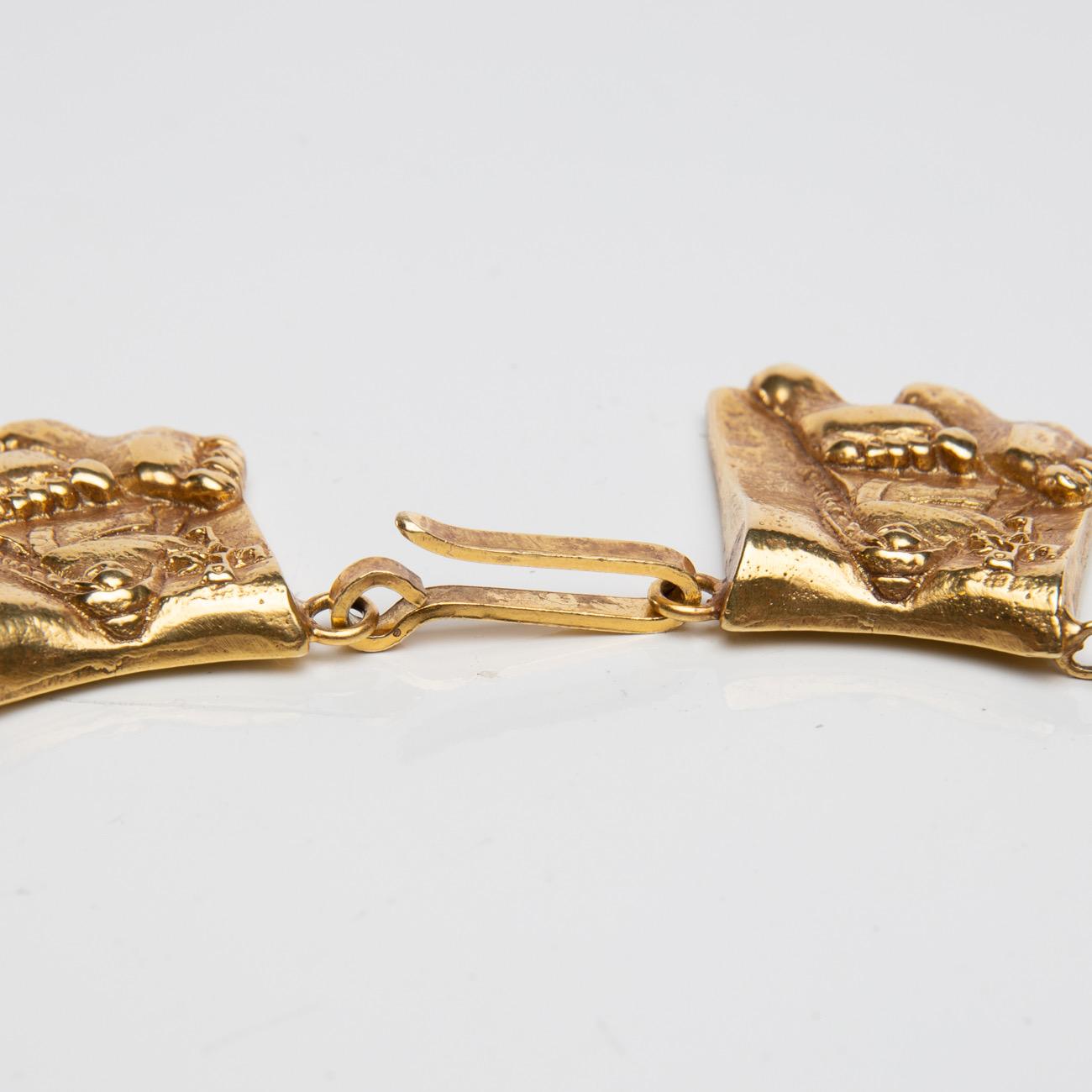 This gilded bronze necklace is made up of 15 links and a clasp. 
Each link represents Line Vautrin's vision of Berthe aux grands pieds (Berthe with big feet). 
To the left of her face, a monogram of Charlemagne is represented. 
 
Berthe aux grands