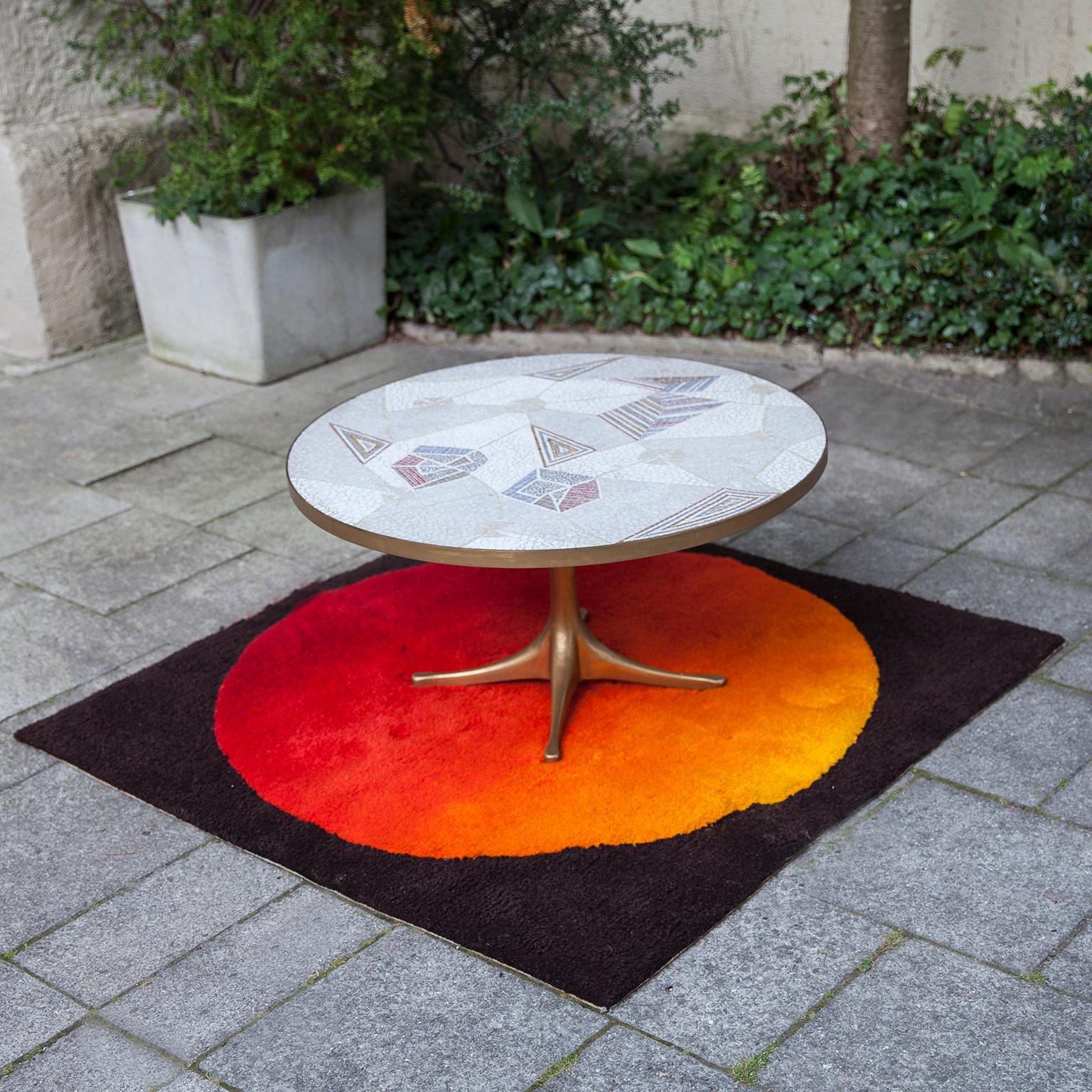 Mosaic coffee table by the German sculptor Berthold Muller, Oerlinghausen (1893-1979).
The table has a round tabletop and beautiful mosaic pattern of glass mosaic tiles and a brass rim on a four star gold painted base. The color of the mosaic tiles