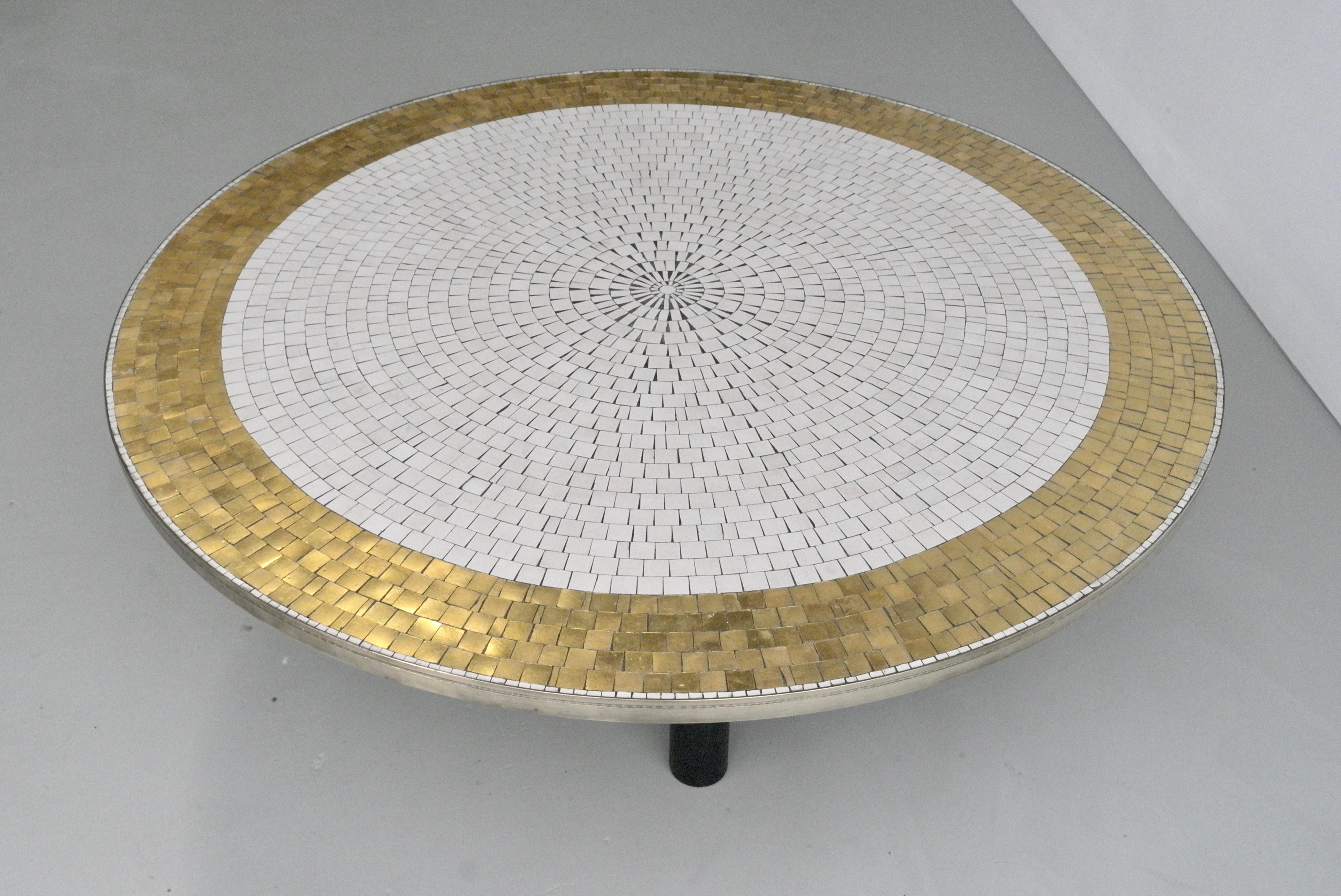Beautiful mid-century coffee table with a round mosaic tile top and brass frame, standing on four black round metal legs. 
Designed and made by Berthold Müller, Oerlinghausen, Germany, in the 1960s. 
The elegant top is composed of white and golden