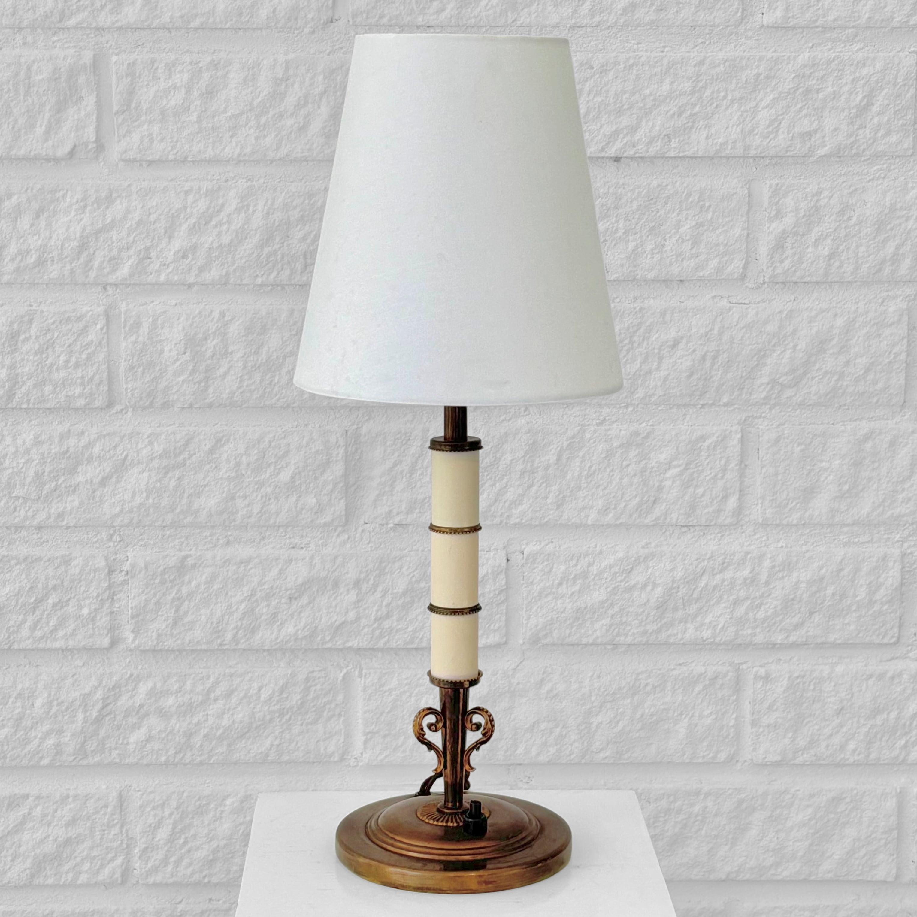 Une belle lampe de table néoclassique conçue par Bertil Brisborg pour le célèbre grand magasin suédois Nordiska Kompaniet dans les années 1930. Fabriquée en laiton poli avec des panneaux cylindriques en acier laqué blanc, elle repose sur une base