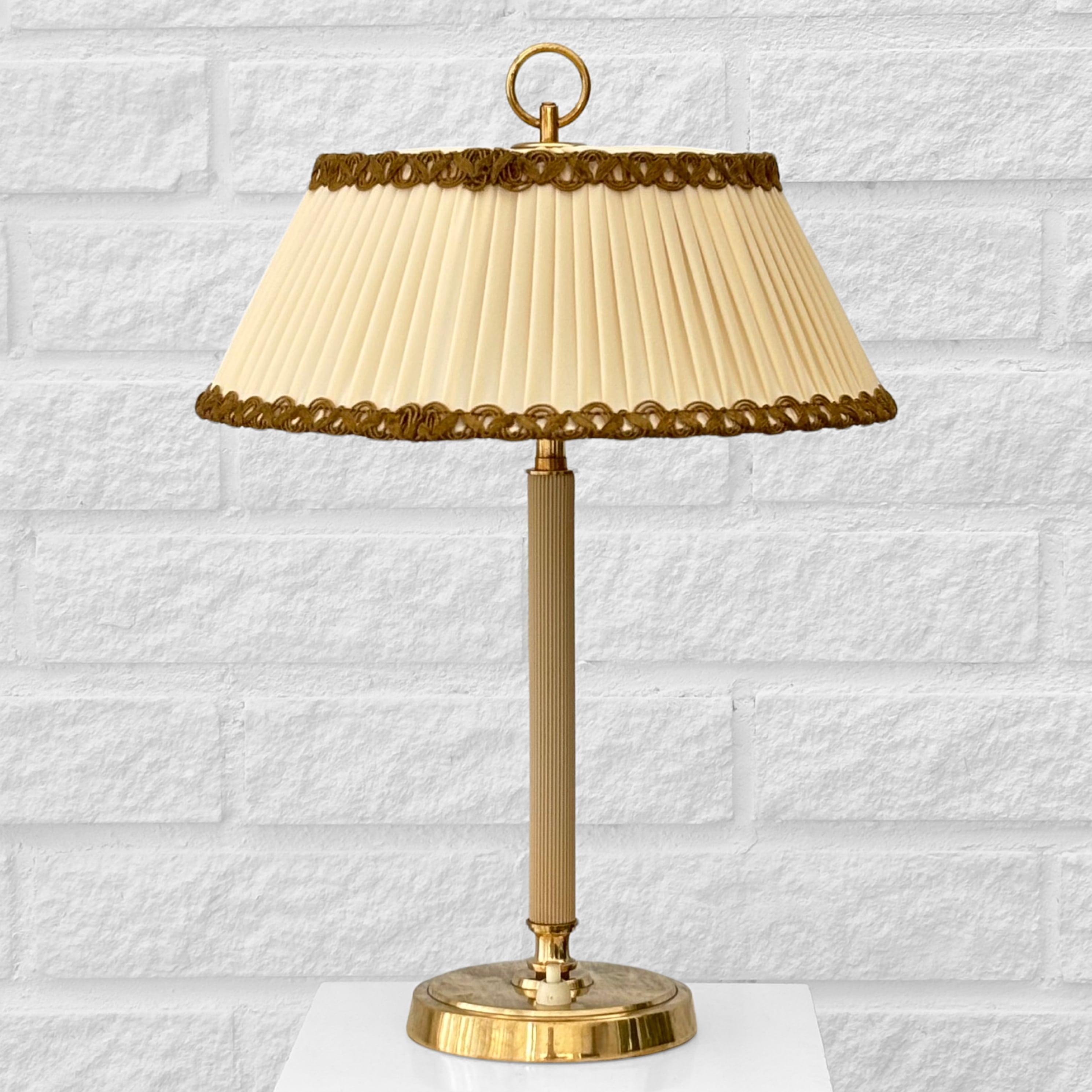 A beautiful table lamp designed by Bertil Brisborg for the renowned Swedish department store Nordiska Kompaniet in the 1940s. Crafted from brass, it features a cylindrical base with an integrated light switch and a brass pillar partly enclosed in