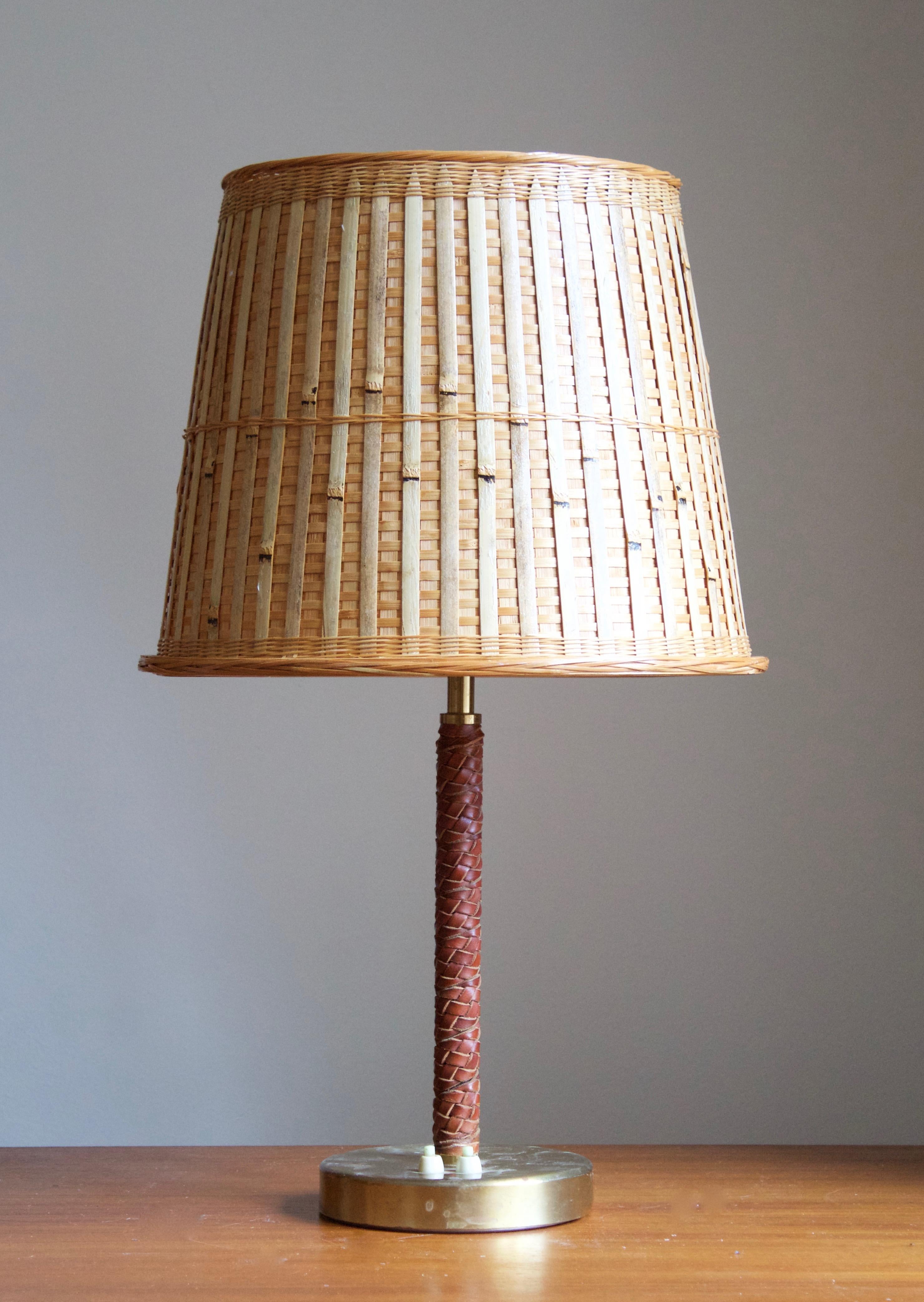 A table lamp, designed by Bertil Brisborg for Nordiska Kompaniet. Produced 1940s.

Features braided leather, brass, and an assorted rattan lampshade.