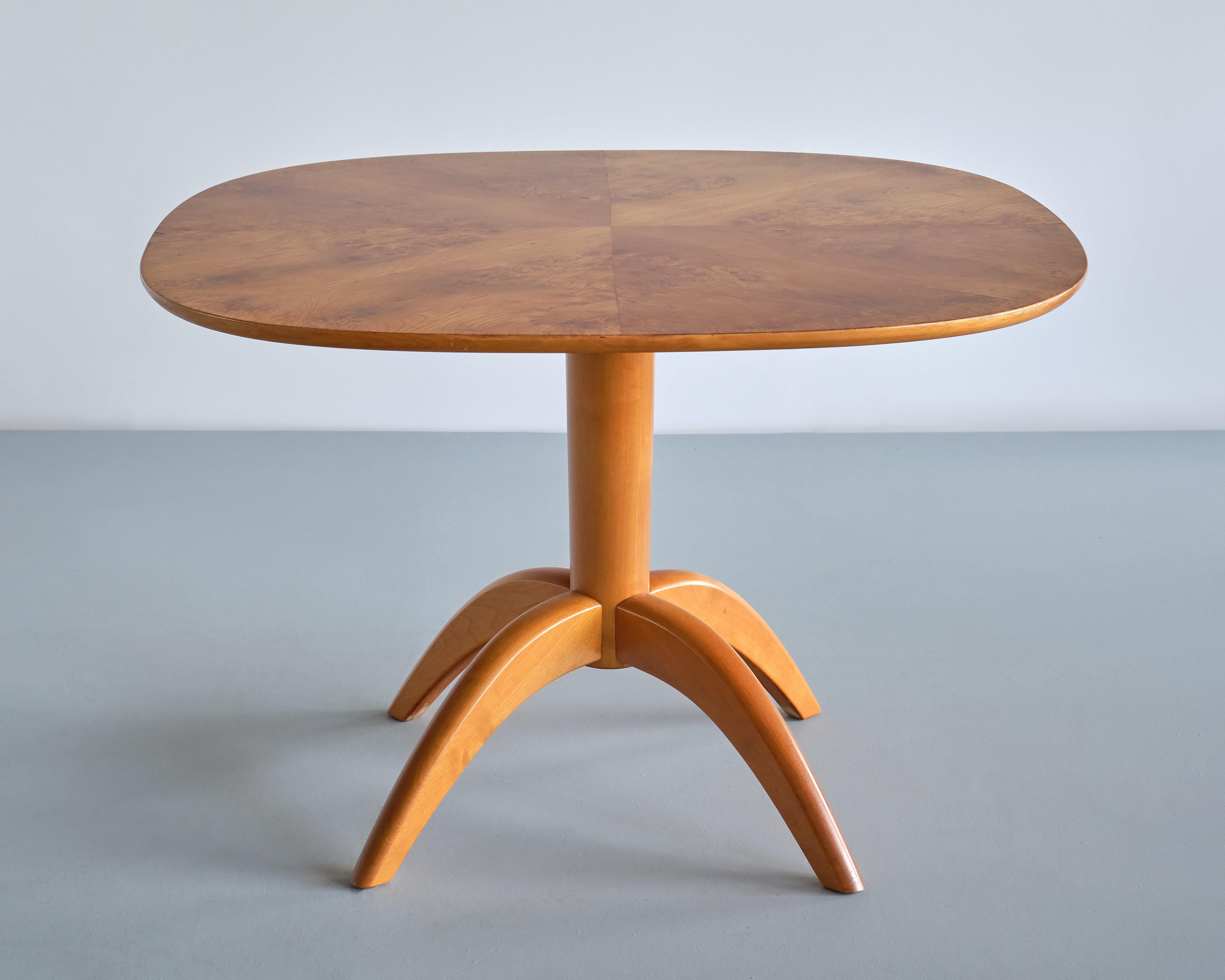 This elegant coffee table was designed by Bertil Söderberg in the mid 1930s. It was produced by the Swedish company Svensk Hemslöjd. 
The design is marked by the sculptural four legged base in solid elm wood.
The top is in a rounded square shape and