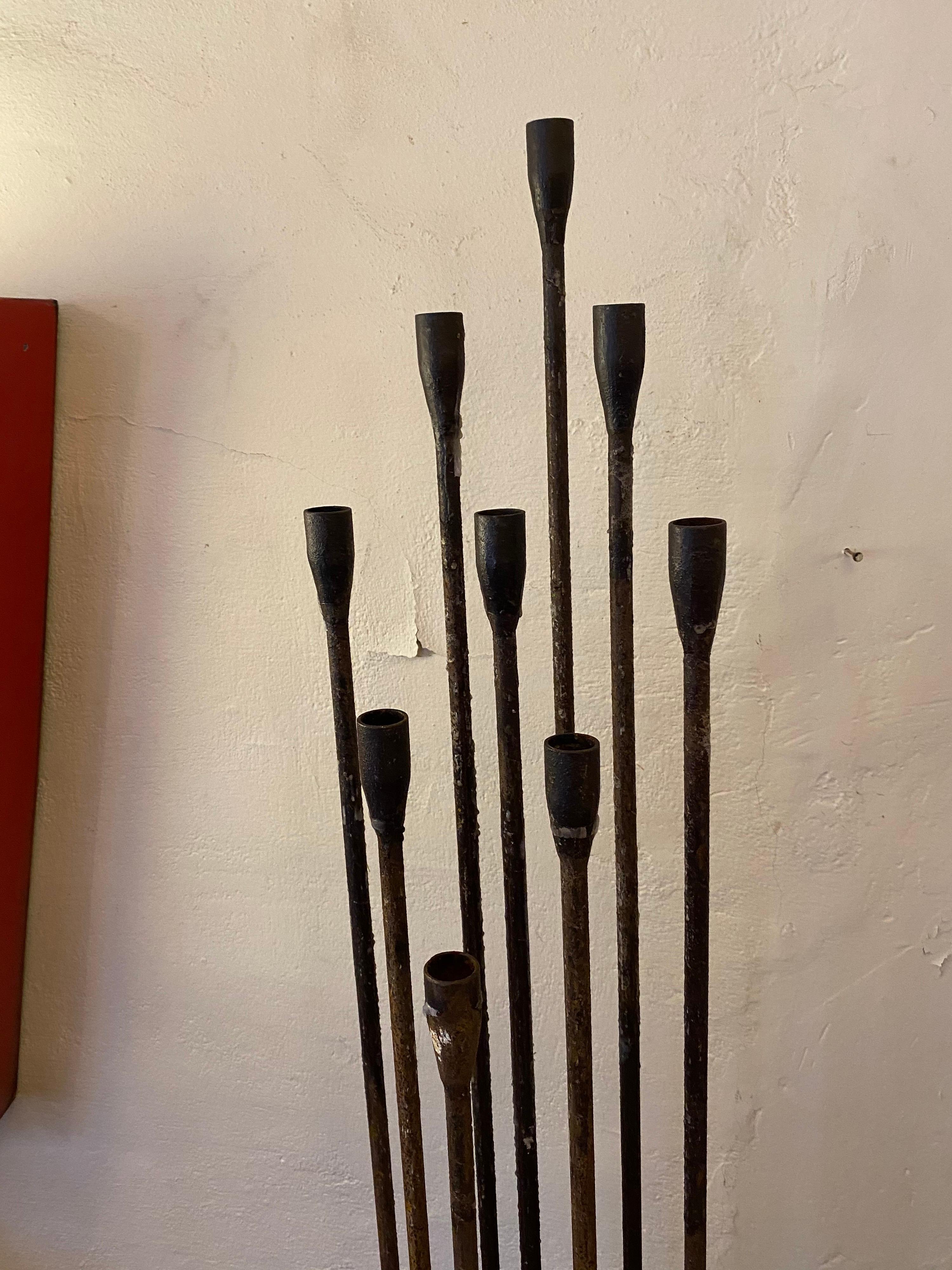 Iron floor candlestand with the look of a Bertoia sculpture. Solid and heavy with a square iron base. Candlestick is made up of 9 rods that are varying heights.
