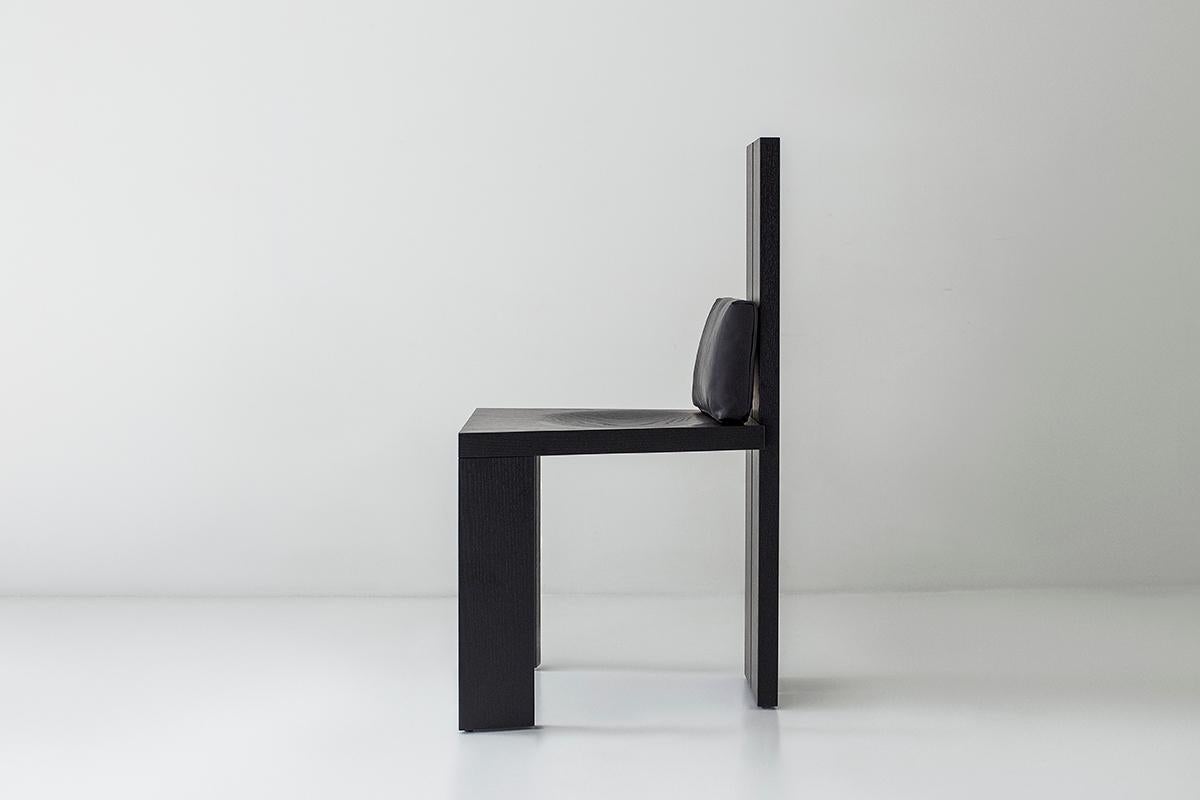 Cette chaise de salle à manger à dossier haut - MarCo en noir - est magnifiquement construite en chêne massif dans l'Ohio, aux États-Unis. La silhouette de la chaise est moderne et architecturale avec une touche d'élégance. Elle est très remarquée