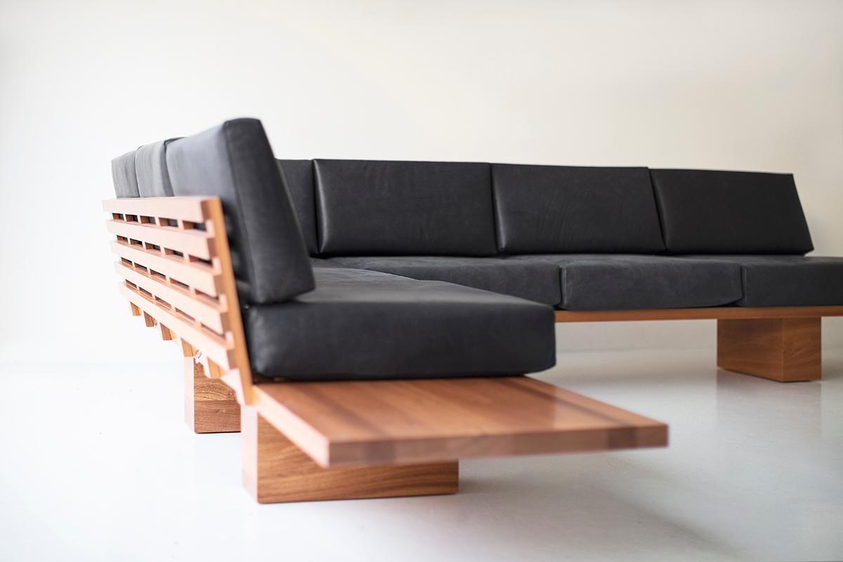 Questo divano in pelle Suelo è costruito in legno massiccio in Ohio, USA. La silhouette di questo divano è semplice, moderna ed elegante, con comodi cuscini per lo schienale e la seduta. La struttura in legno può essere realizzata in versione a