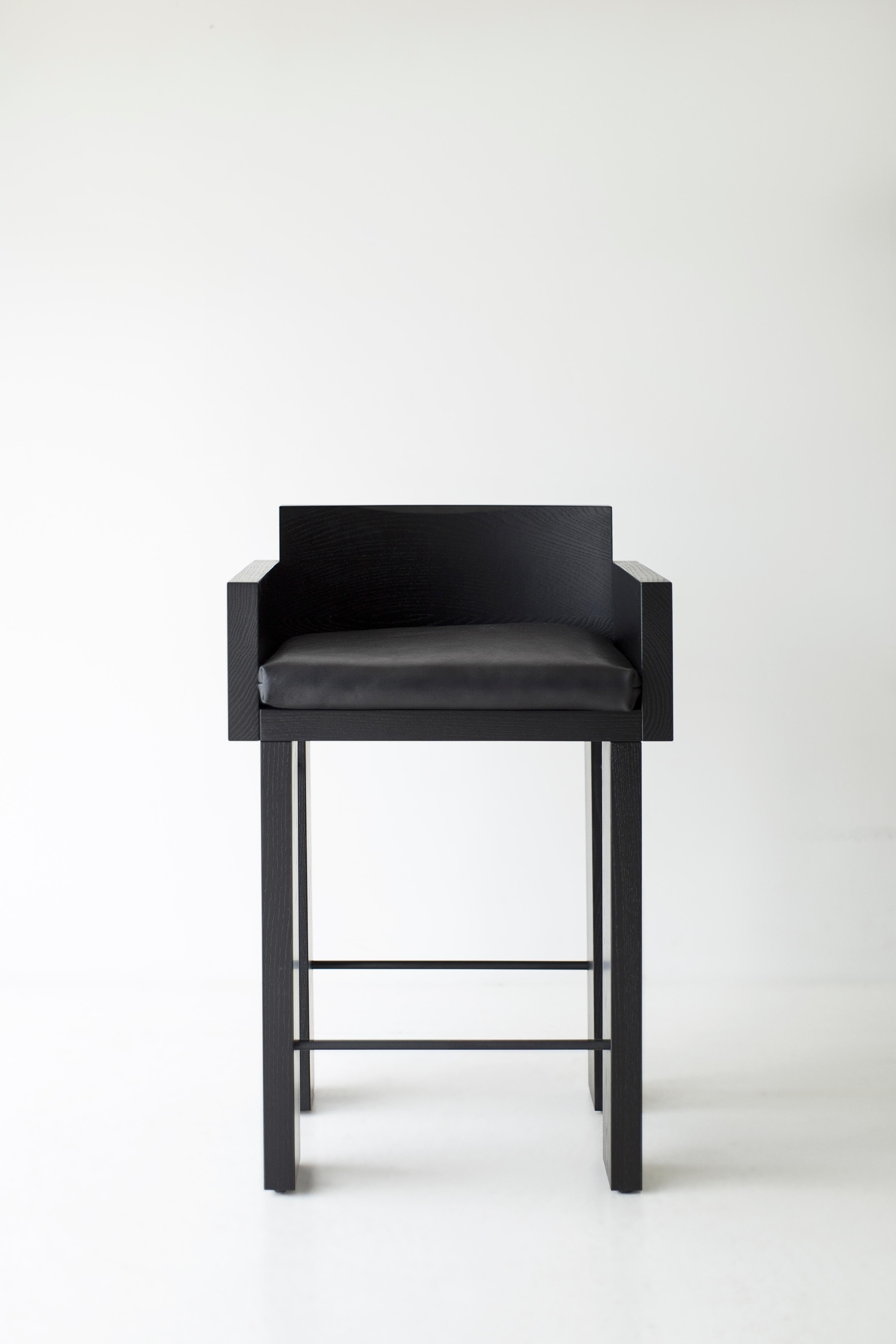 Questi sgabelli da banco Chile in Oak Oak annerito sono costruiti in legno massiccio in Ohio, USA. Gli sgabelli sono robusti e moderni, con un comodo cuscino in tessuto a trama fitta del colore che preferisci. Le eleganti aste in metallo nero