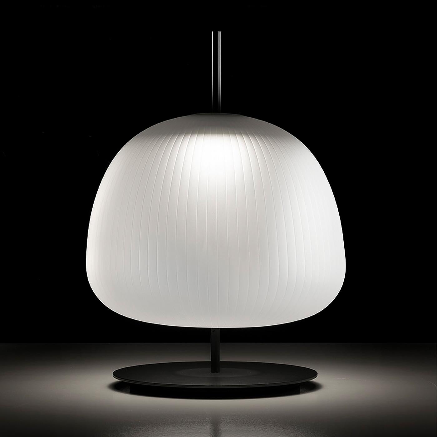 Table lamp bearing the name of an ancient divinity, made of blown frosted glass characterized by thin lines that create a pleated effect.