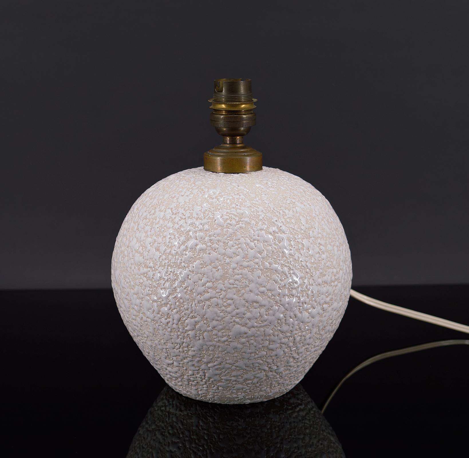 Elegant enameled ceramic ball table lamp.
Spherical shape, with white enamel on a light cream background.

Art Deco, France, around 1930.
In the style of the productions of Jean Besnard. 

In good condition, electricity checked.

Dimensions :
Height
