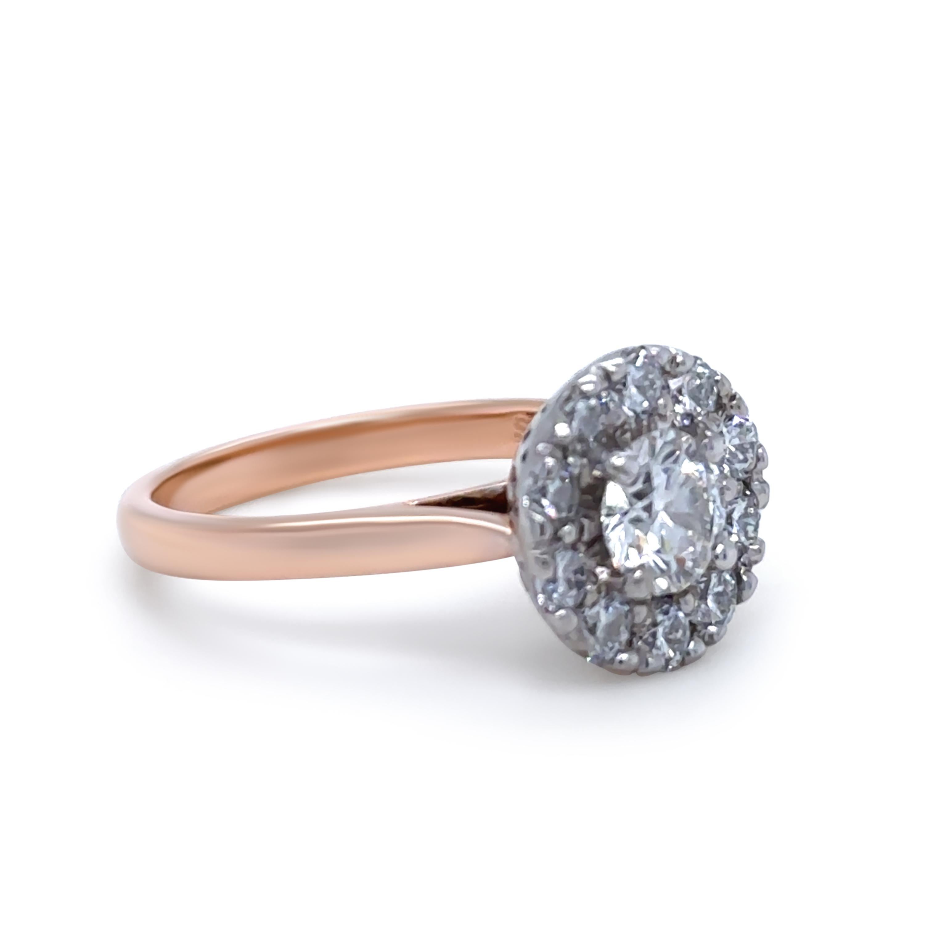An elegant 18ct Rose Gold Diamond Cluster Engagement Ring, featuring a central Round Brilliant Cut Diamond of 0.709ct, graded F Colour and SI2 Clarity (AUS Cert 201 4M21 159), set in 4 claws. 

The center stone is surrounded by 10 Round Brilliant