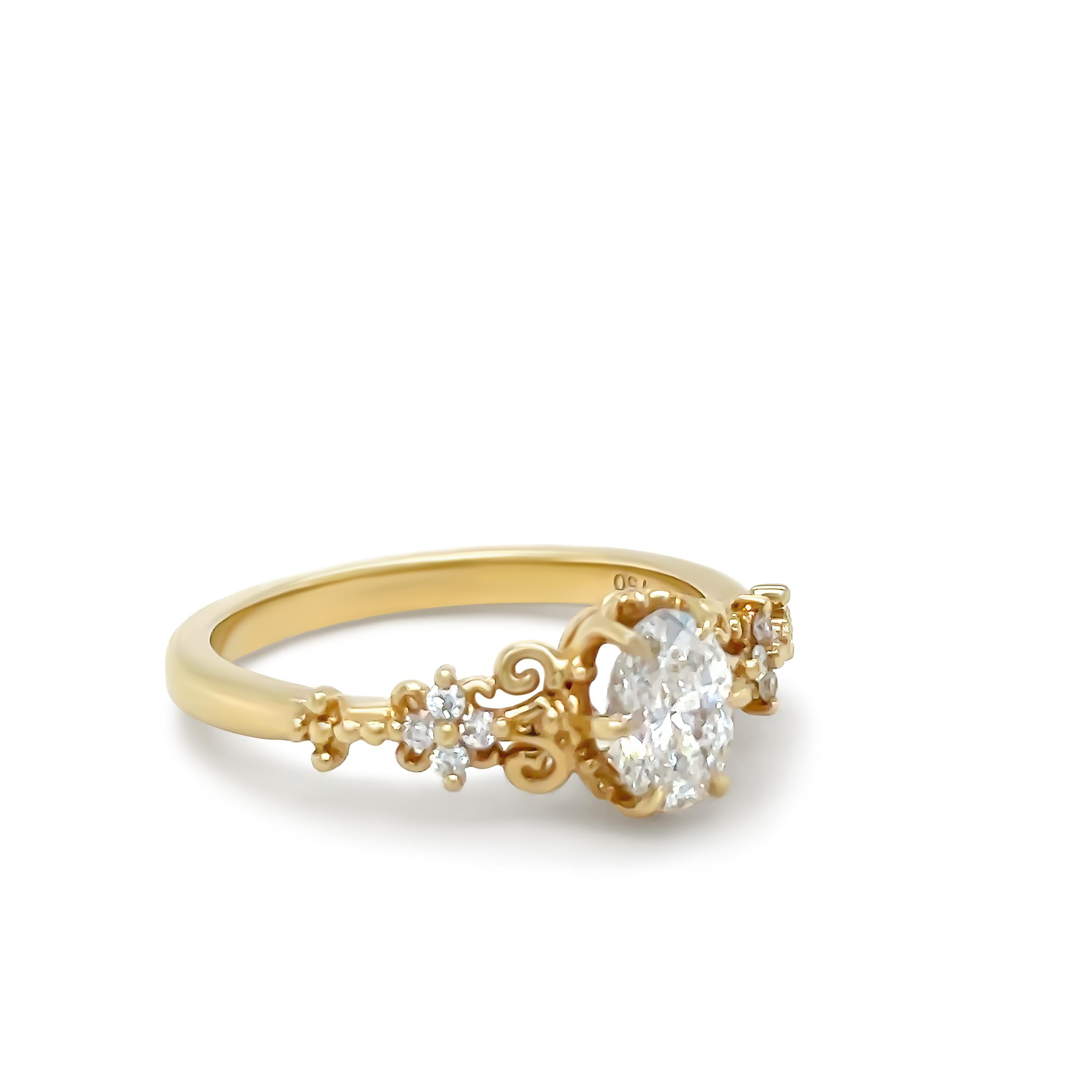 Bague à diamant sur mesure, en or jaune 18ct. Un diamant ovale de taille brillant de couleur F et de pureté SI2 pesant 0,60 ct est serti sur six griffes.

Elle est également sertie de 8 diamants ronds de taille Brilliante sertis sur les épaules sur