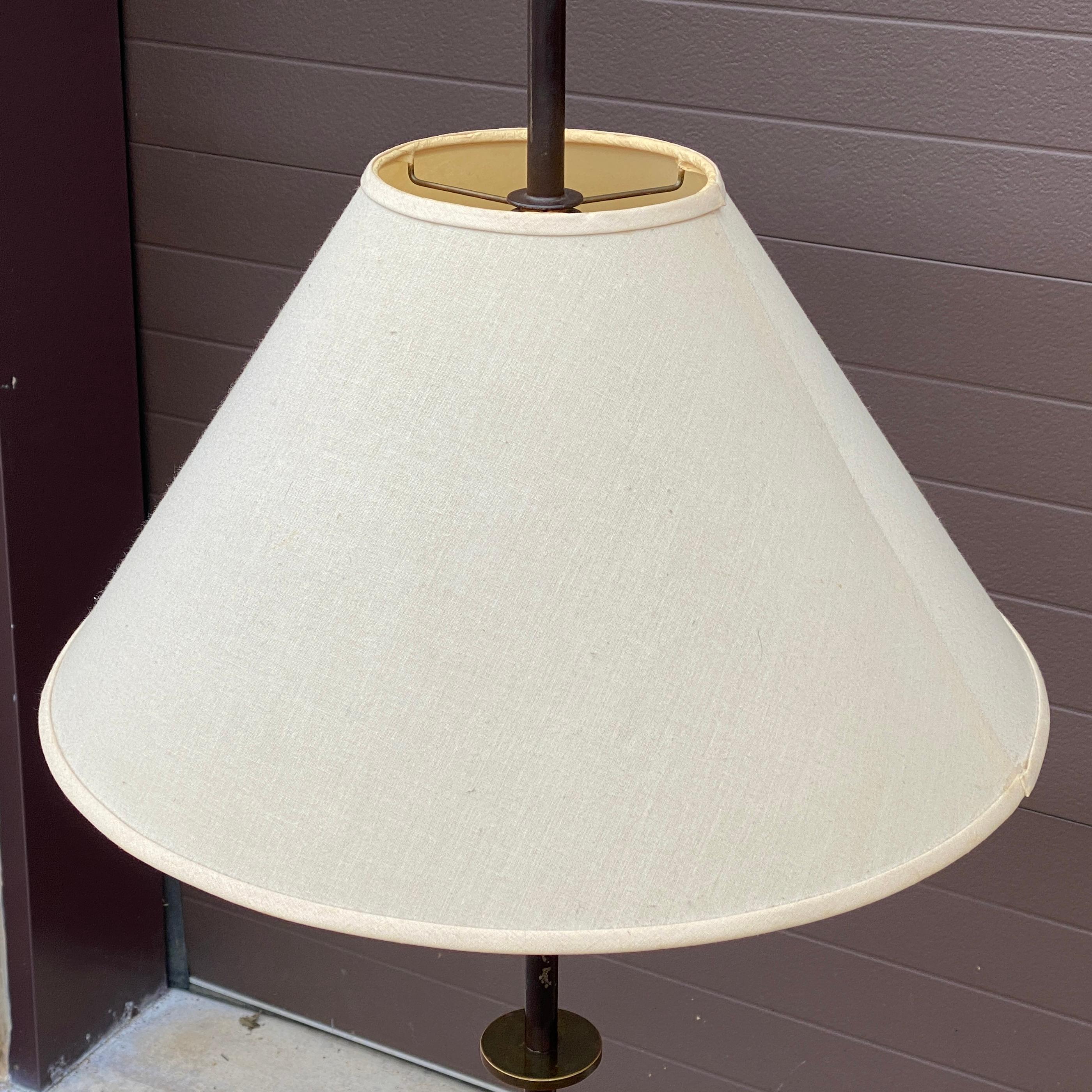 Lampadaire tripode en laiton et acier des années 1950, dans le style de Tommi Parzinger.
Acier émaillé avec fleuron épique en laiton en forme d'oiseau stylisé et détails de disques en laiton sur la tige.
Doubles douilles d'ampoules à chaîne de