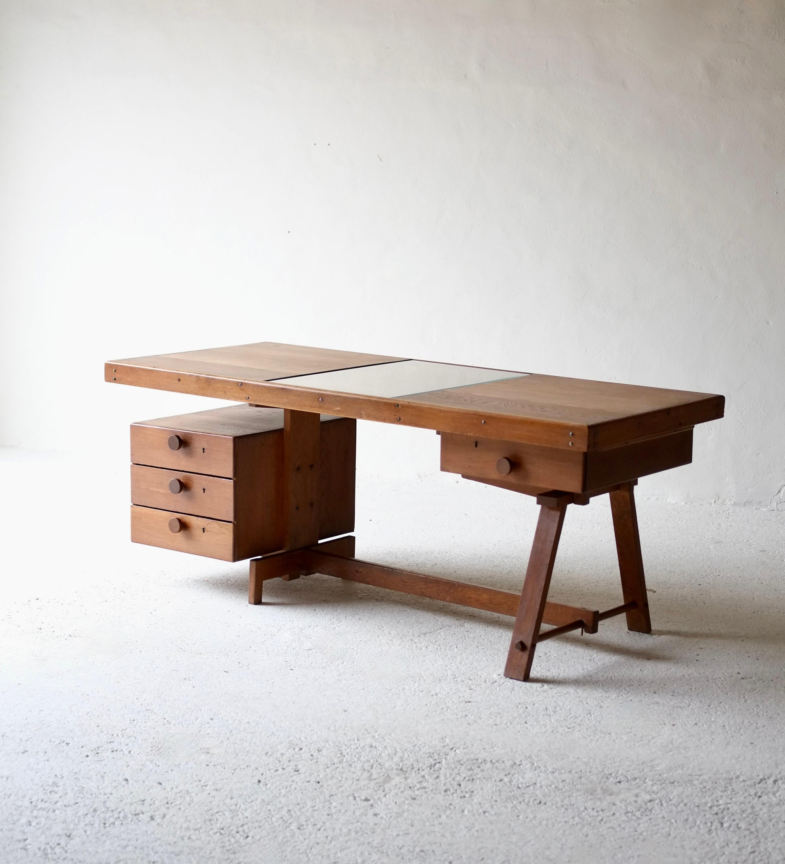 A bespoke oak wood desk.

France, circa 1950's.

Featuring a glass desk top centre piece the desk appears to have been custom made for a craftsman. 

In very good restored condition with no movement to the joints. The glass has been newly replaced.