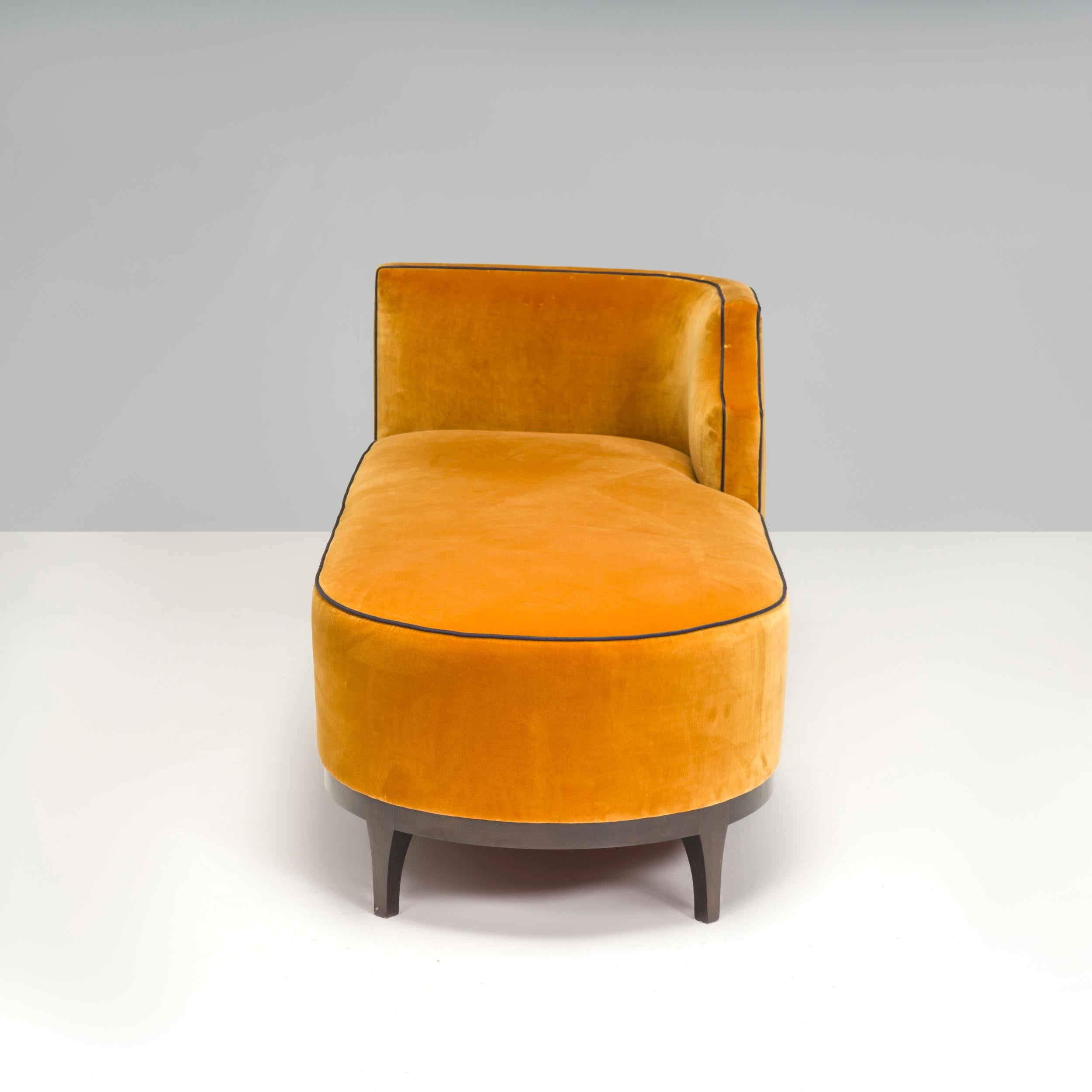 Beautifully curved, this Art Deco style bespoke chaise longue is upholstered in mustard yellow velvet and sits dark wooden legs with an additional central support.

The back of the sofa is curved, creating a striking silhouette. The contrast pipping