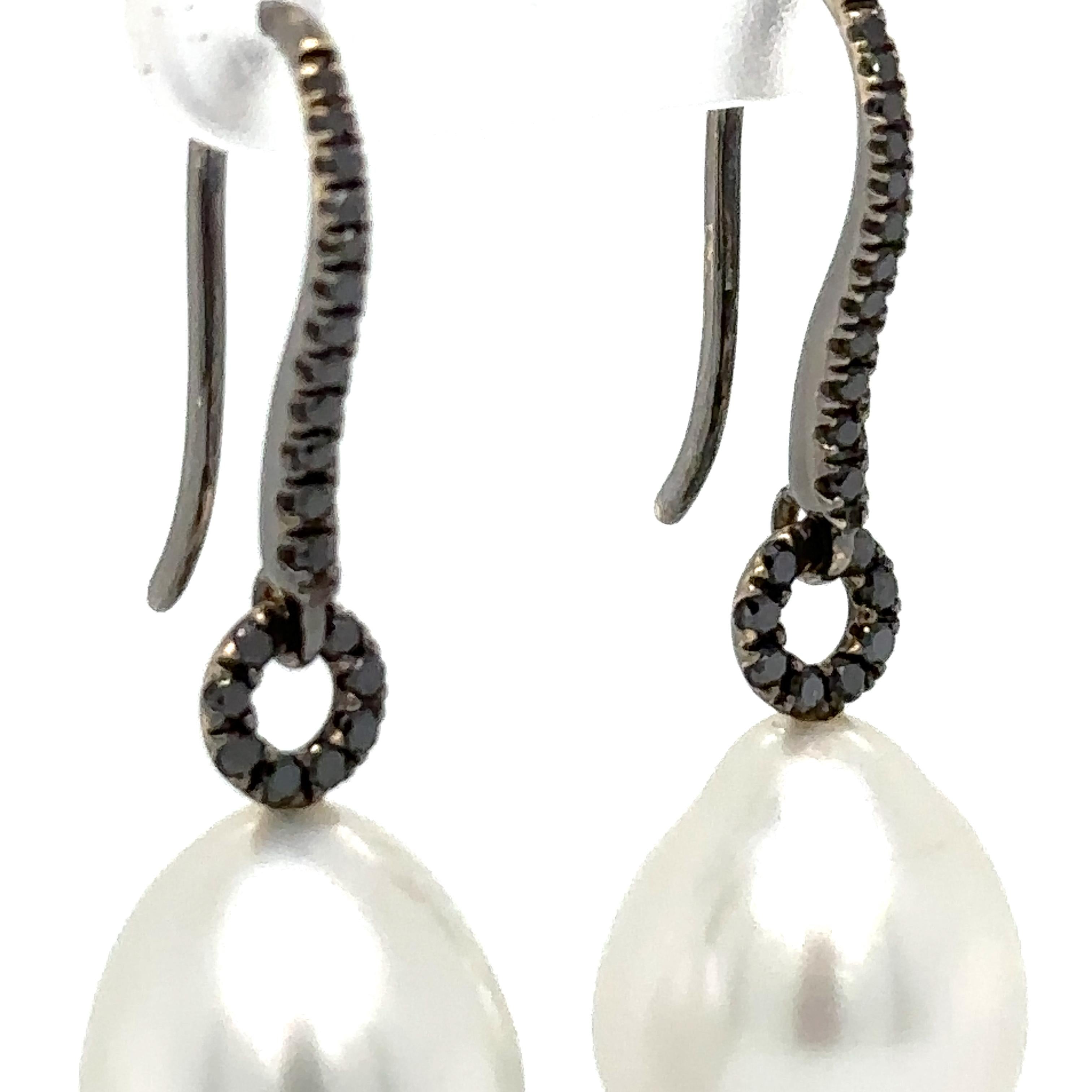 A Pair Of South Sea Pearl And Diamond Drop Earrings. Each earring with a drop shape South Sea cultured pearl below 21 treated black round diamonds claw set in 18ct black rhodium plated fittings.

Origin: Broome

Diamonds 42 = 0.31ct