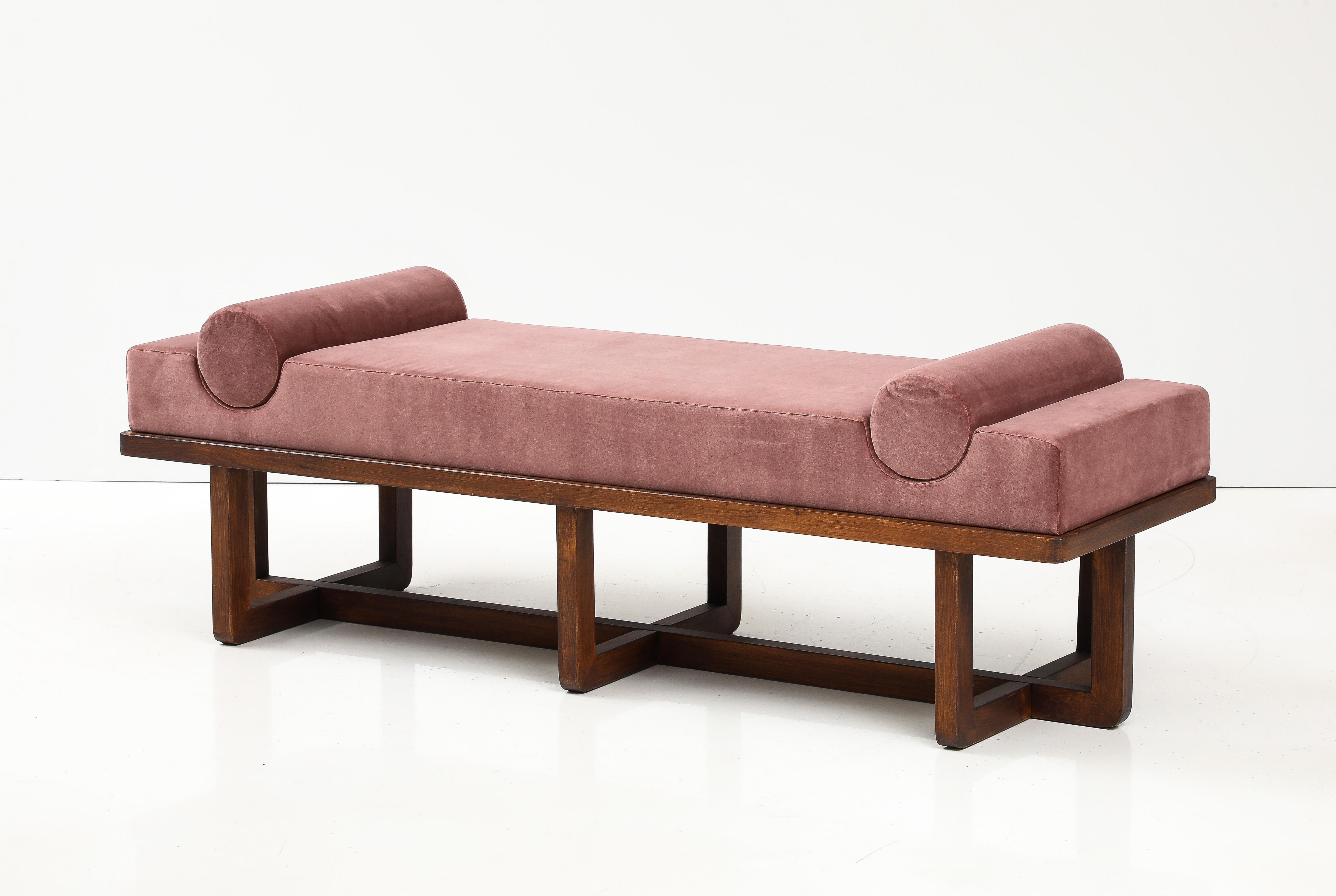 This bespoke sculptural bench was handcrafted by a master carpenter in Florence, Italy. A rectangular, thick padded seat upholstered in an imported antique rose colored velvet is offset by round bolster cushions that are inset into the padded