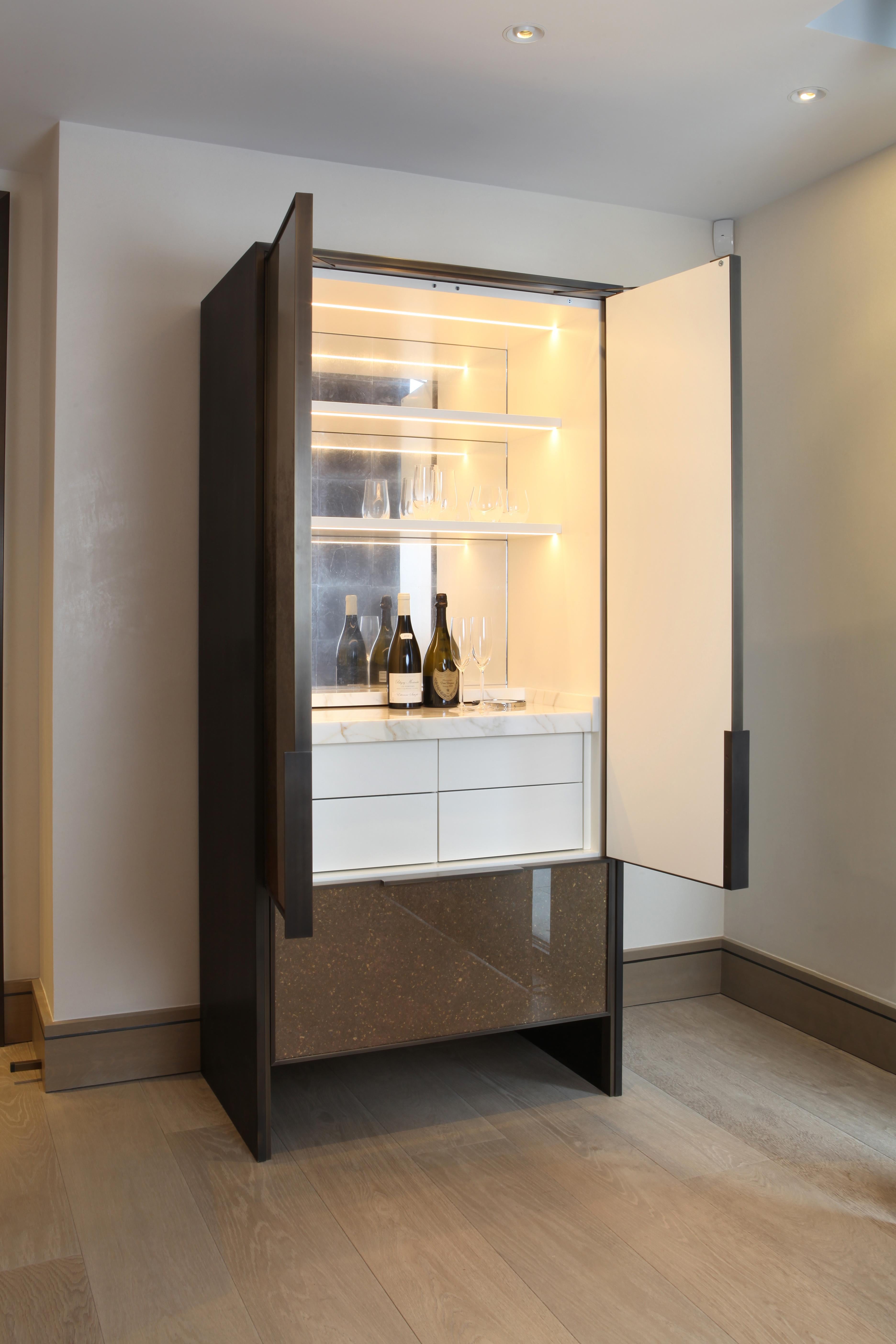 Designed by award winning Los Angeles based designer Luis Ortega. 

Freestanding cocktail cabinet created form a bronze panel carcase; with bronze framed doors with verre églomisé bronze and gold glass inset panels.
Internally illuminated interior