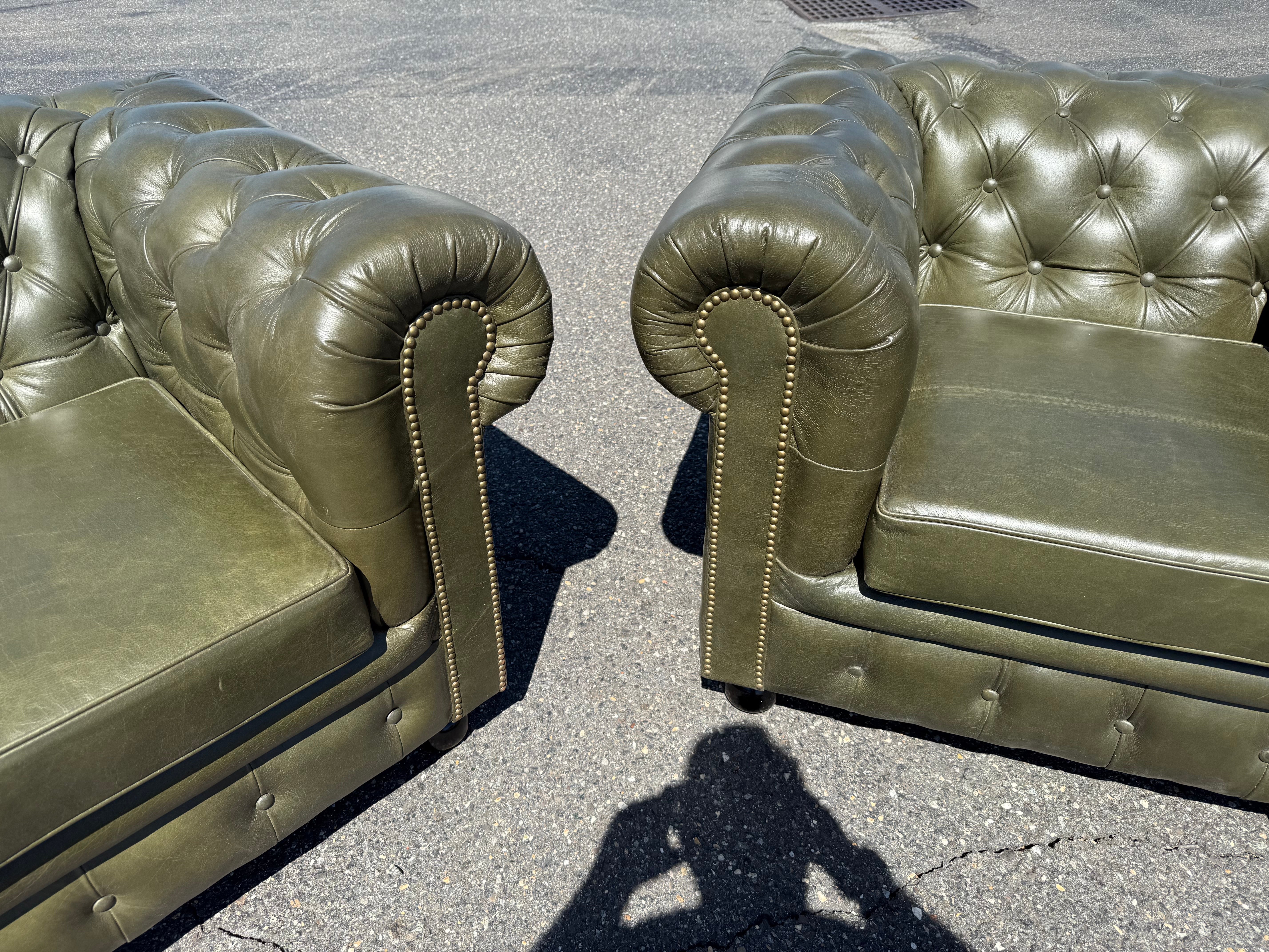This handsome pair of English-made Chesterfield chairs showcases the timeless elegance and durability that has made this design a classic for centuries. Upholstered in rich green leather, the chairs feature the iconic deep button-tufted back and