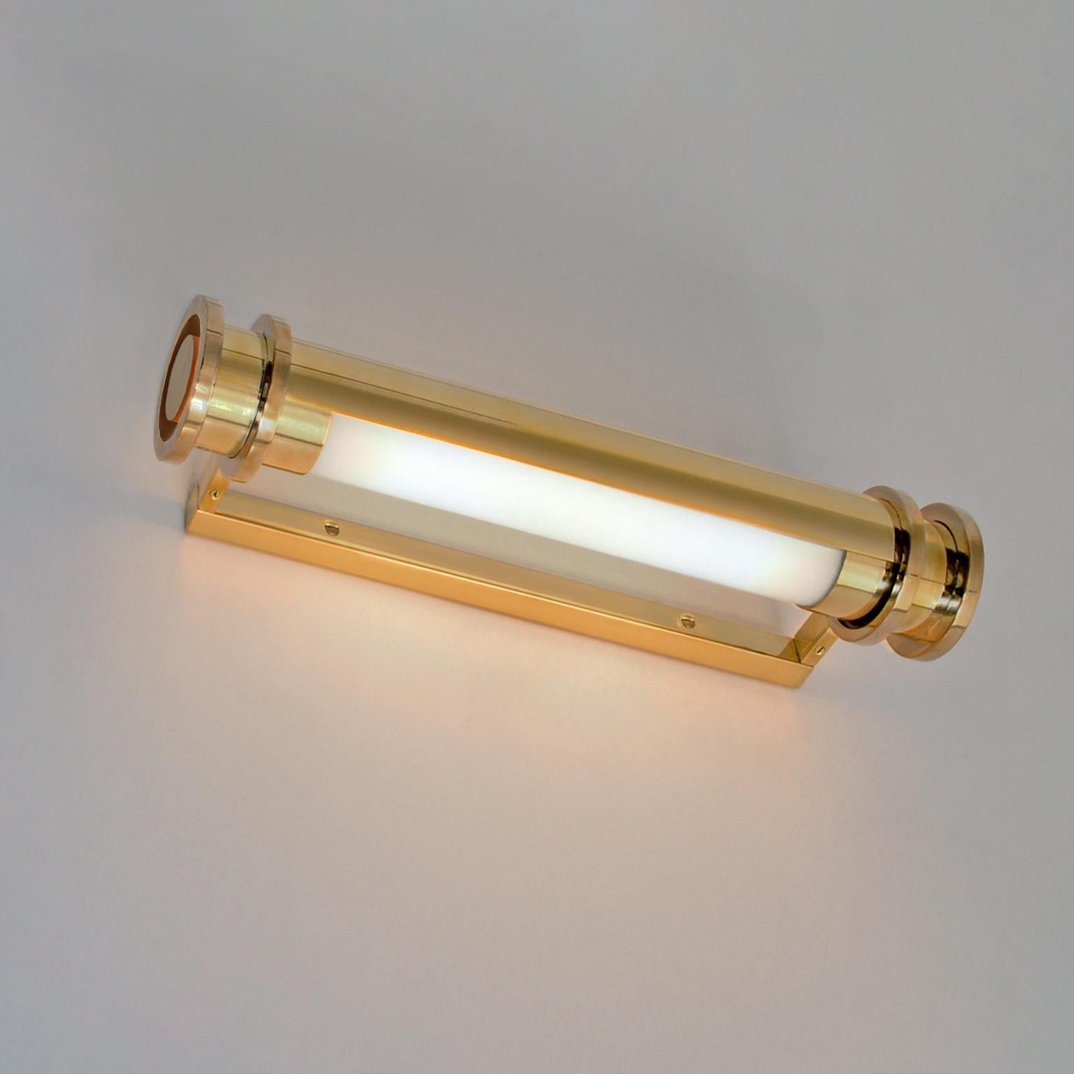 Aplique cilíndrico hecho a medida con pantalla reflectora ajustable. La luz está hecha de latón pulido y cristal opalino. También disponible en la versión sin pantalla reflectora.