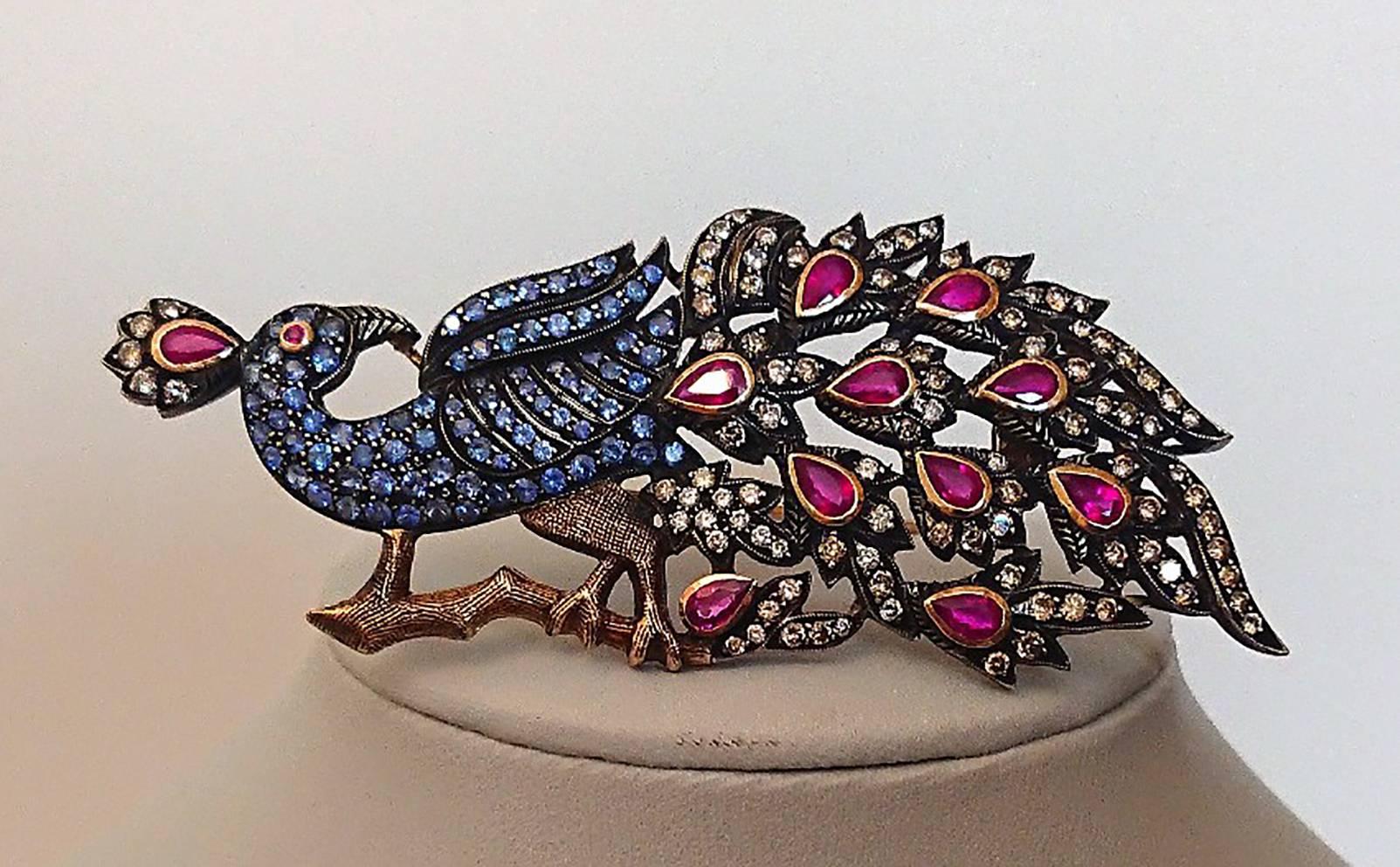 An amazing custom made peacock brooch with diamonds, Sapphires and rubies.
Measuring an impressive 7.5cm x 3.4cm
The main body of the peacock is set with approx 1.20ct of Sapphire.
The tail has 10 x 0.20ct pear rubies and an array of genuine