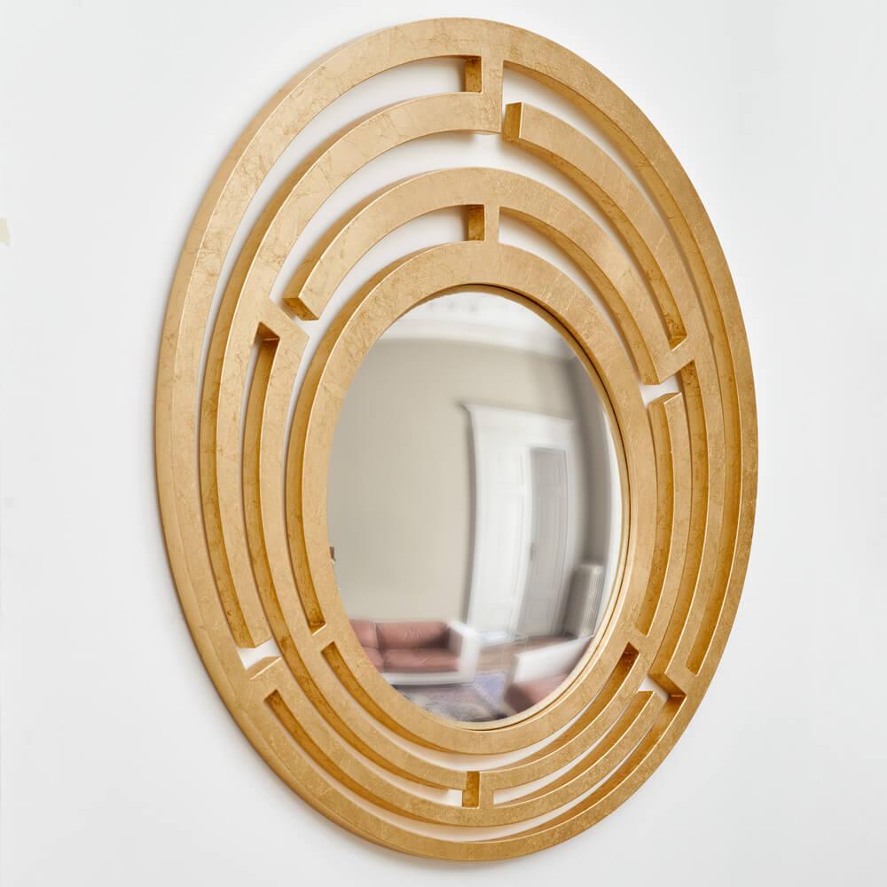 The “Nemesi” model is a striking convex mirror, featuring an intricately articulated frame, expertly covered in gold leaf. The frame’s pattern evokes a geometric labyrinth, adding a sense of depth and movement, while the gold finish lends a timeless