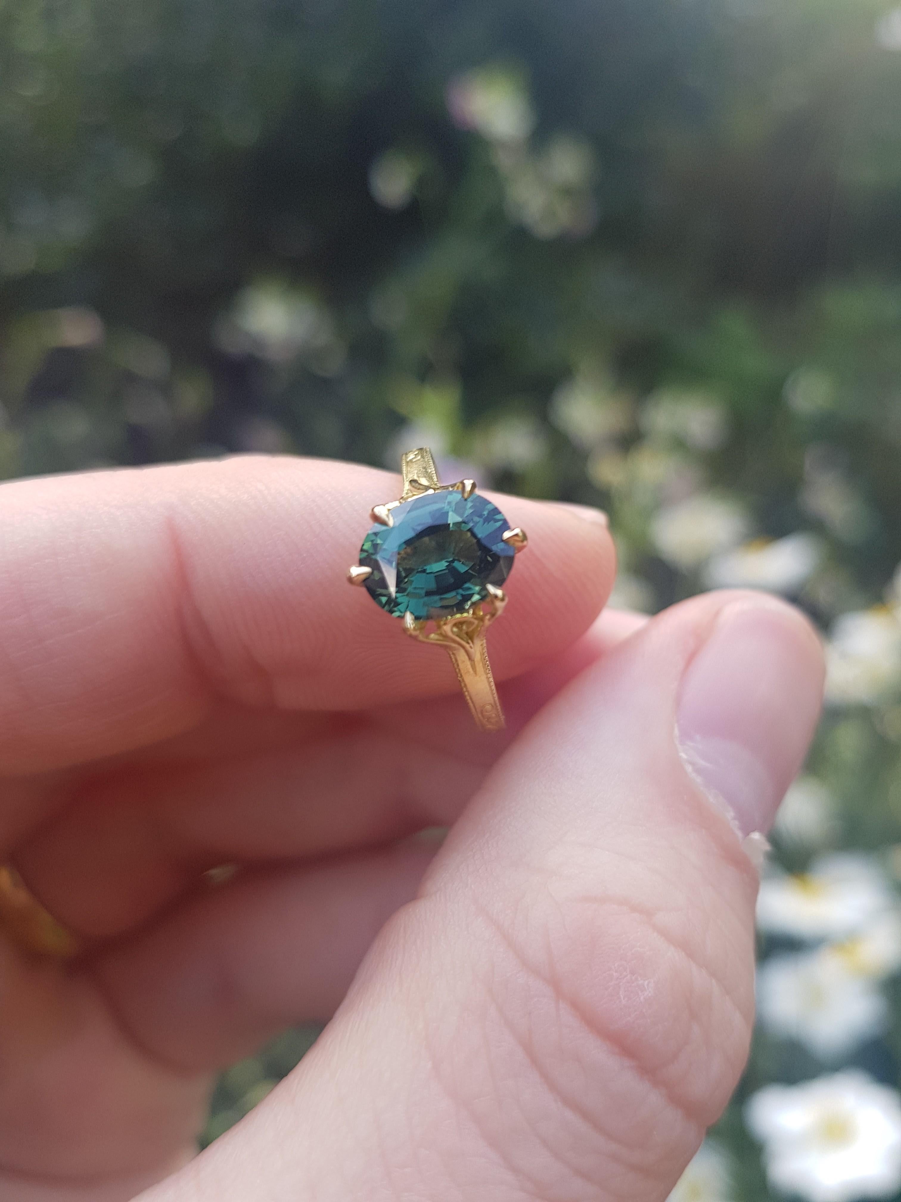 Set in intricately engraved 18 carat yellow gold, this is an unusual 2.12 carat green sapphire in a unique design recently handmade for one of our customers.